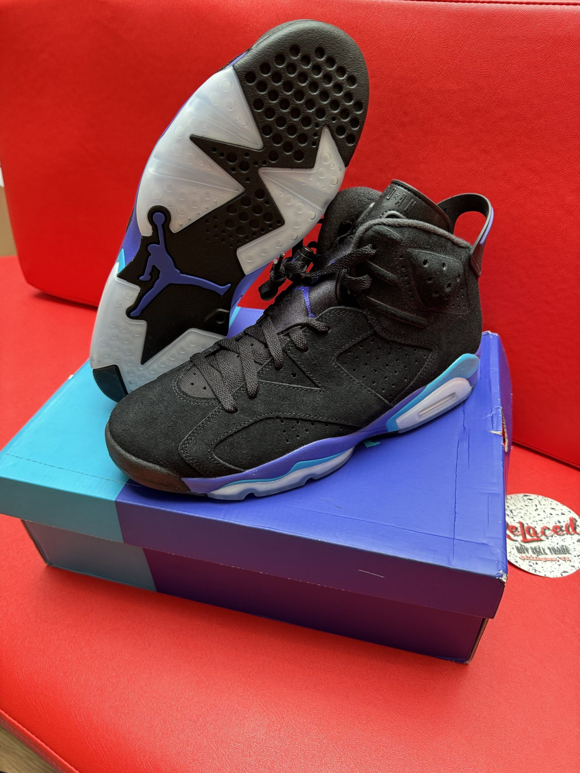 Black and purple Air Jordan 6 sneakers on blue box, showcasing sole details.