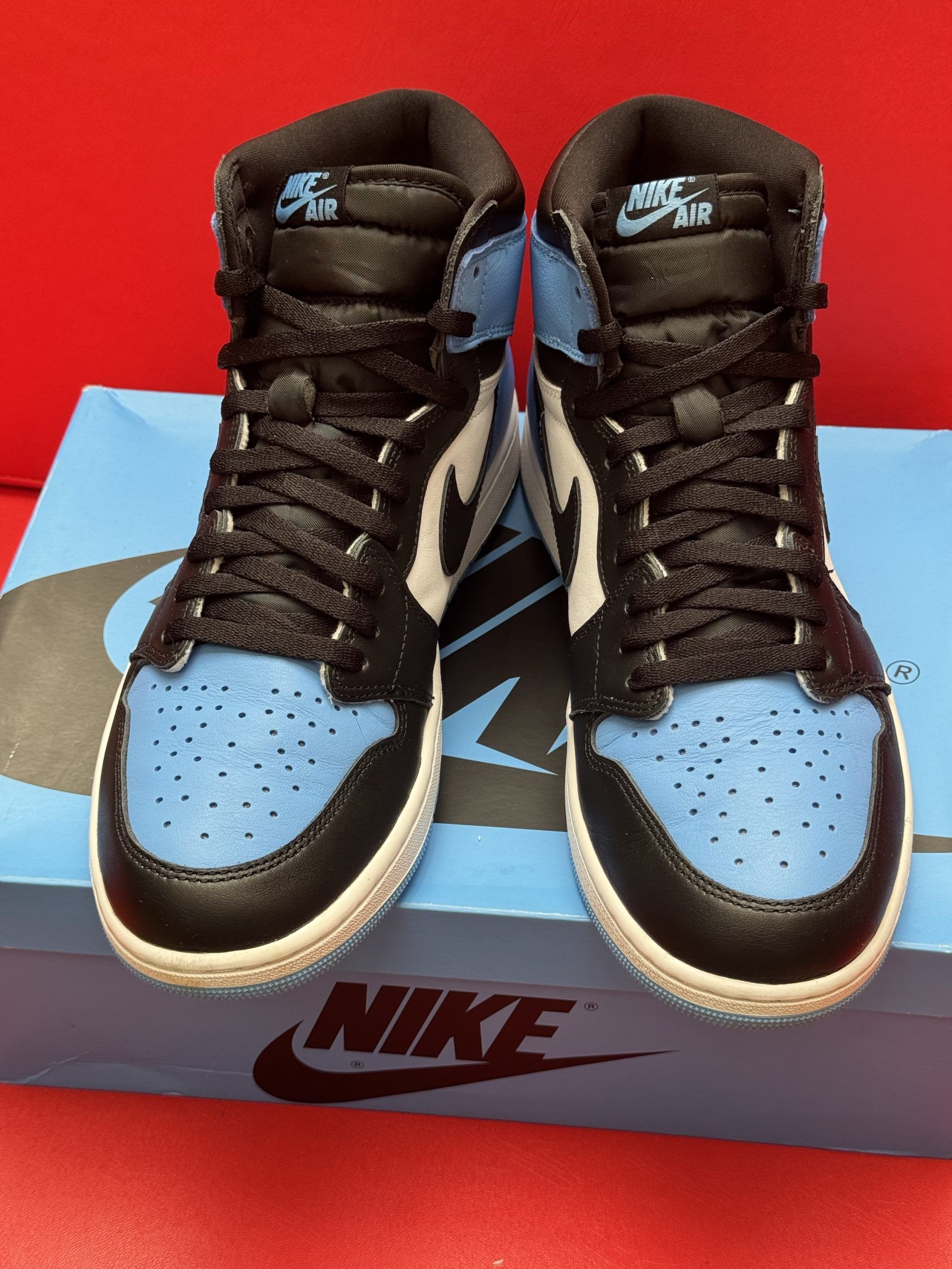 Blue and black Air Jordan 1 sneaker on its box, with a light blue sole visible.