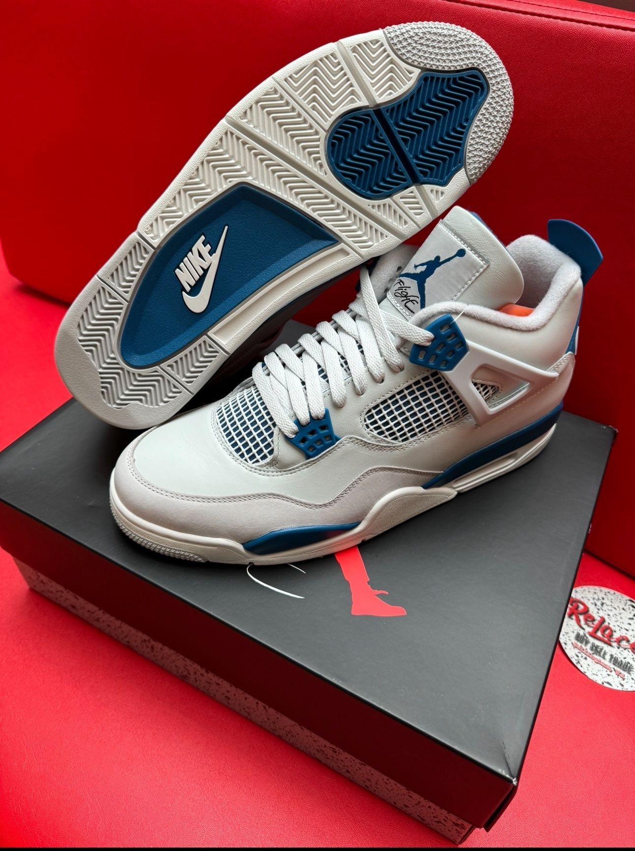 Air Jordan 4 sneakers, white, blue, and grey, on a shoebox.