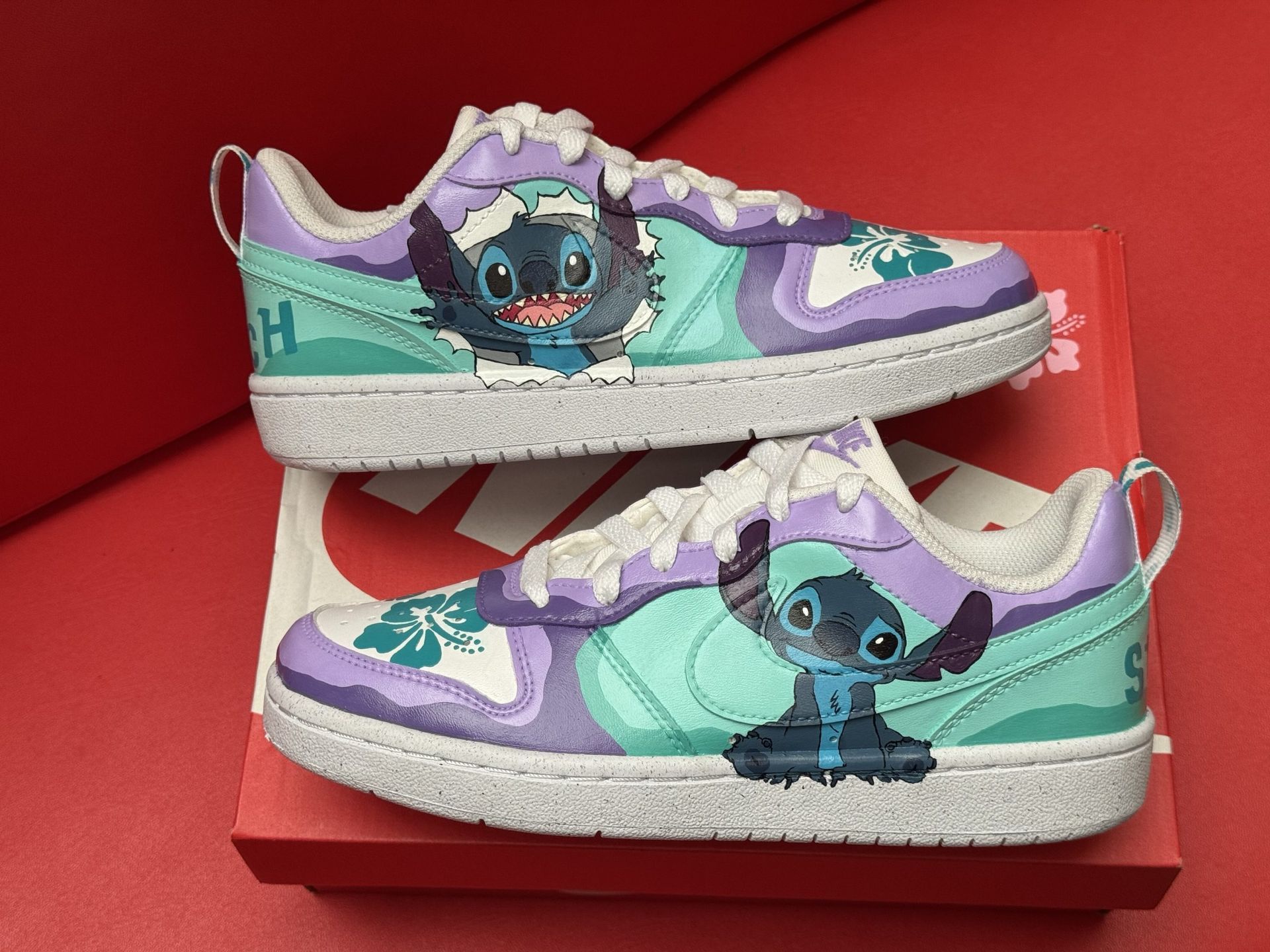 A Nike sneaker featuring Stitch, a blue Disney character, sits on a box, with a figurine of Stitch.