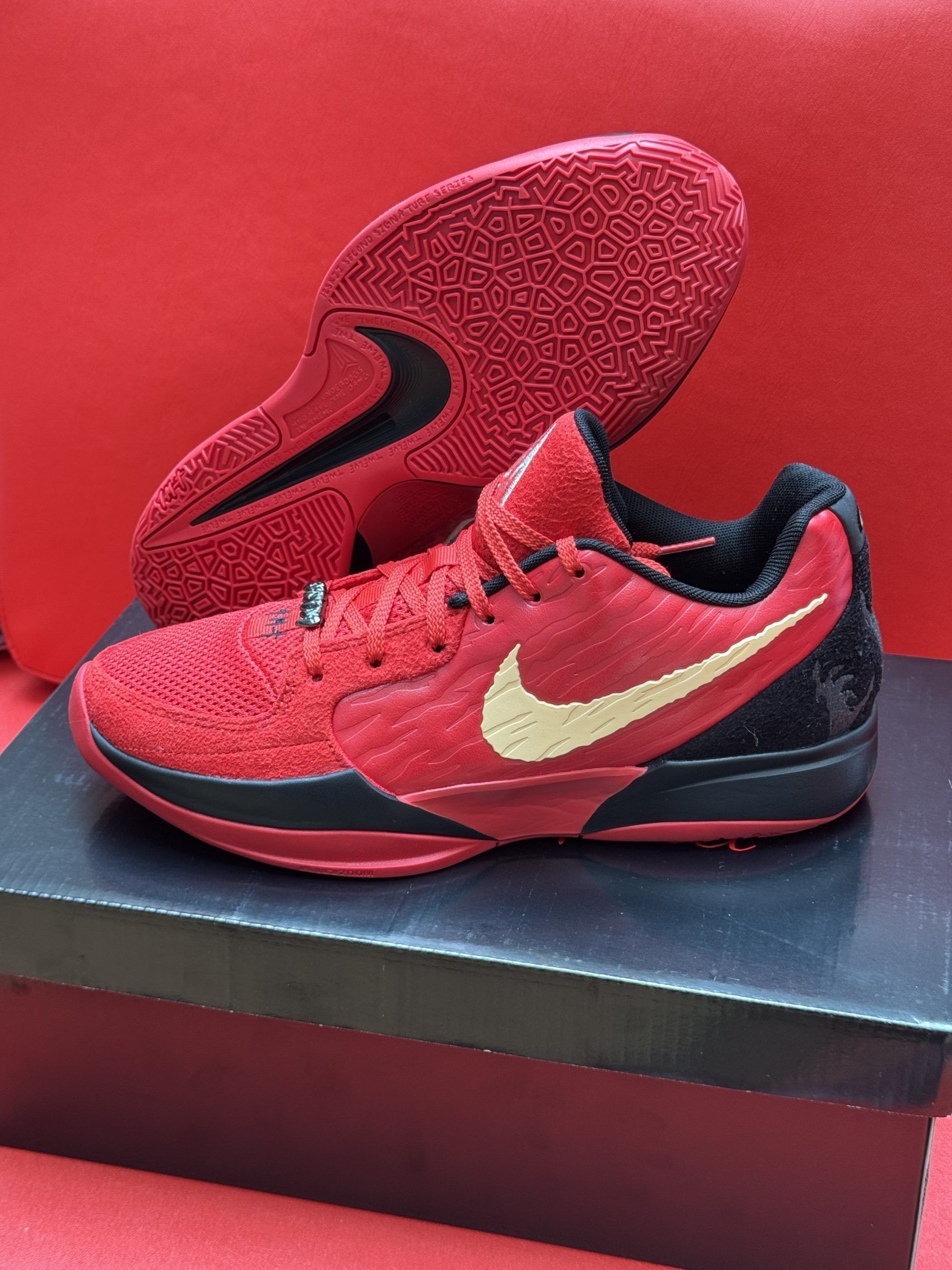 Red Nike basketball sneakers with a gold swoosh on a black box.