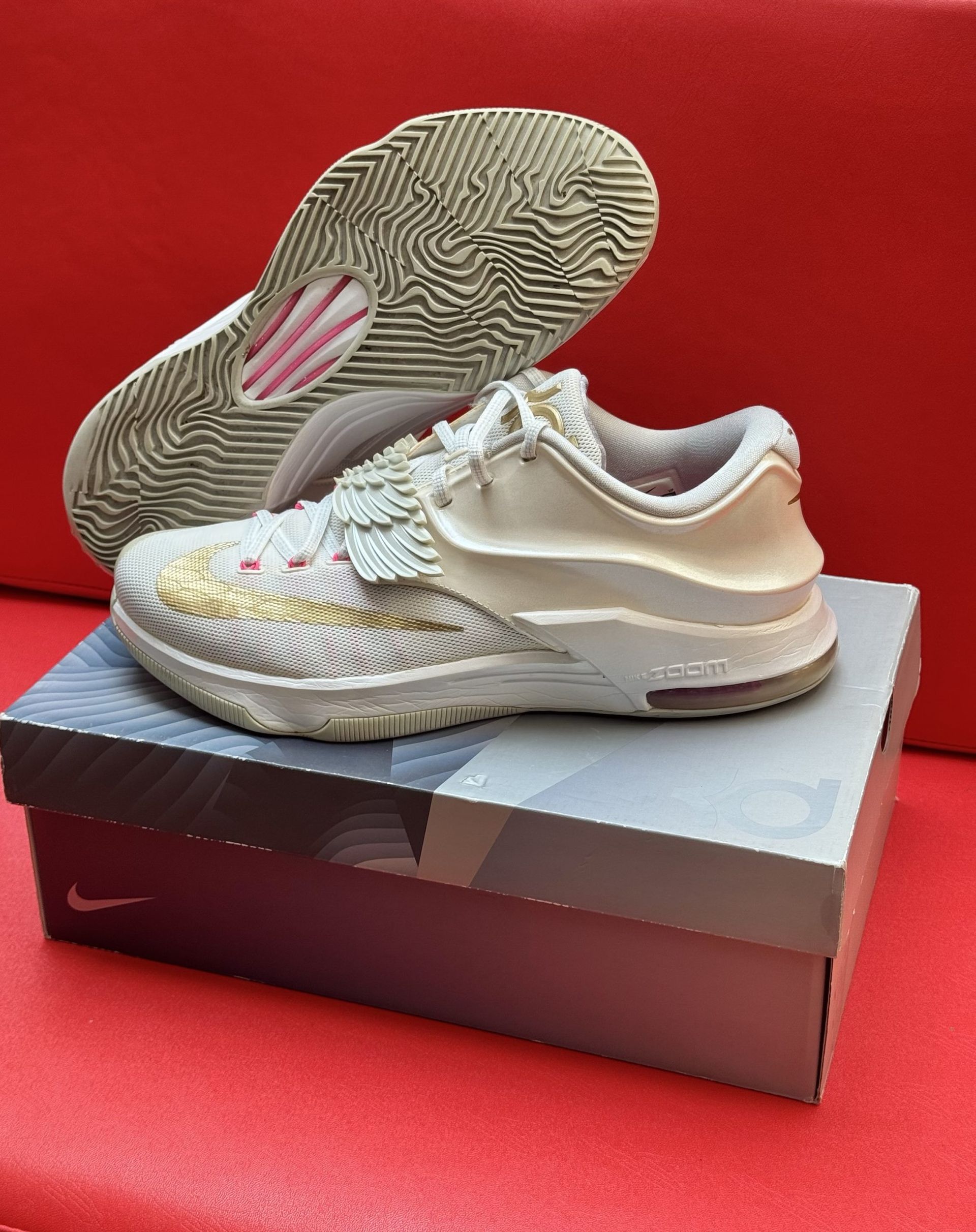 White Nike KD 14 basketball shoe on top of a box, red background.
