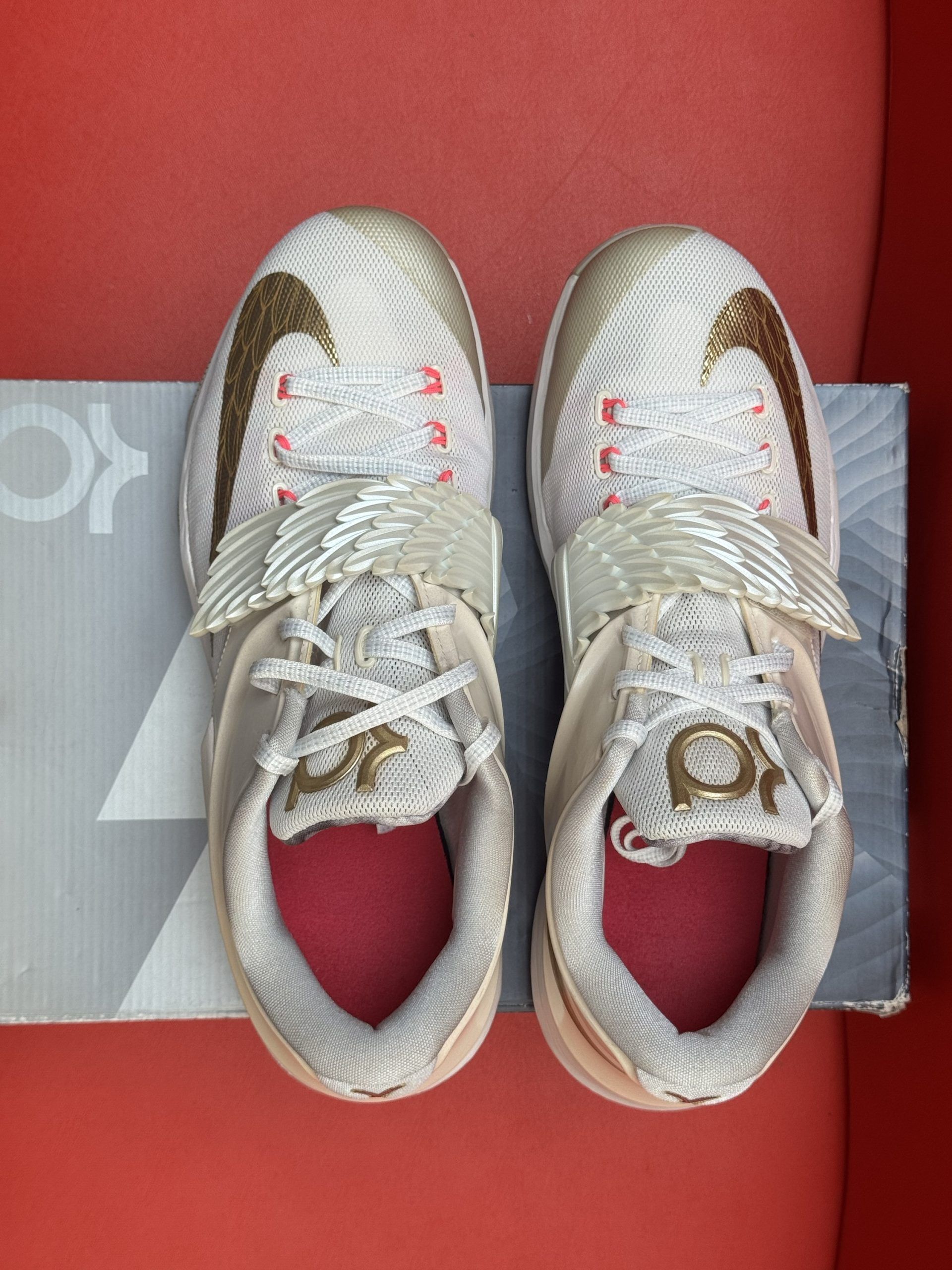 White Nike KD 14 basketball shoe on top of a box, red background.