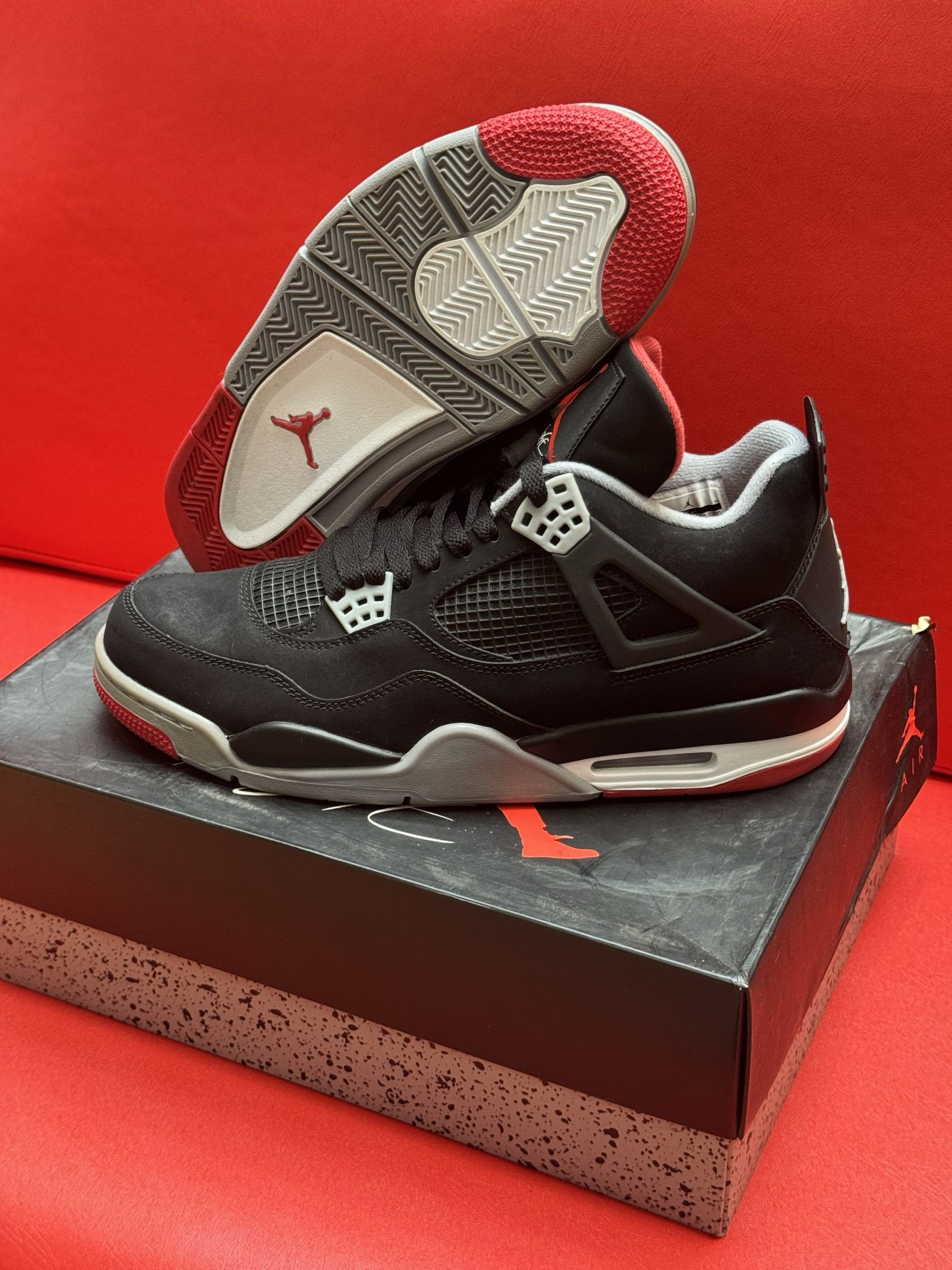 Black and red Air Jordan 4 sneakers on a box, sole visible.