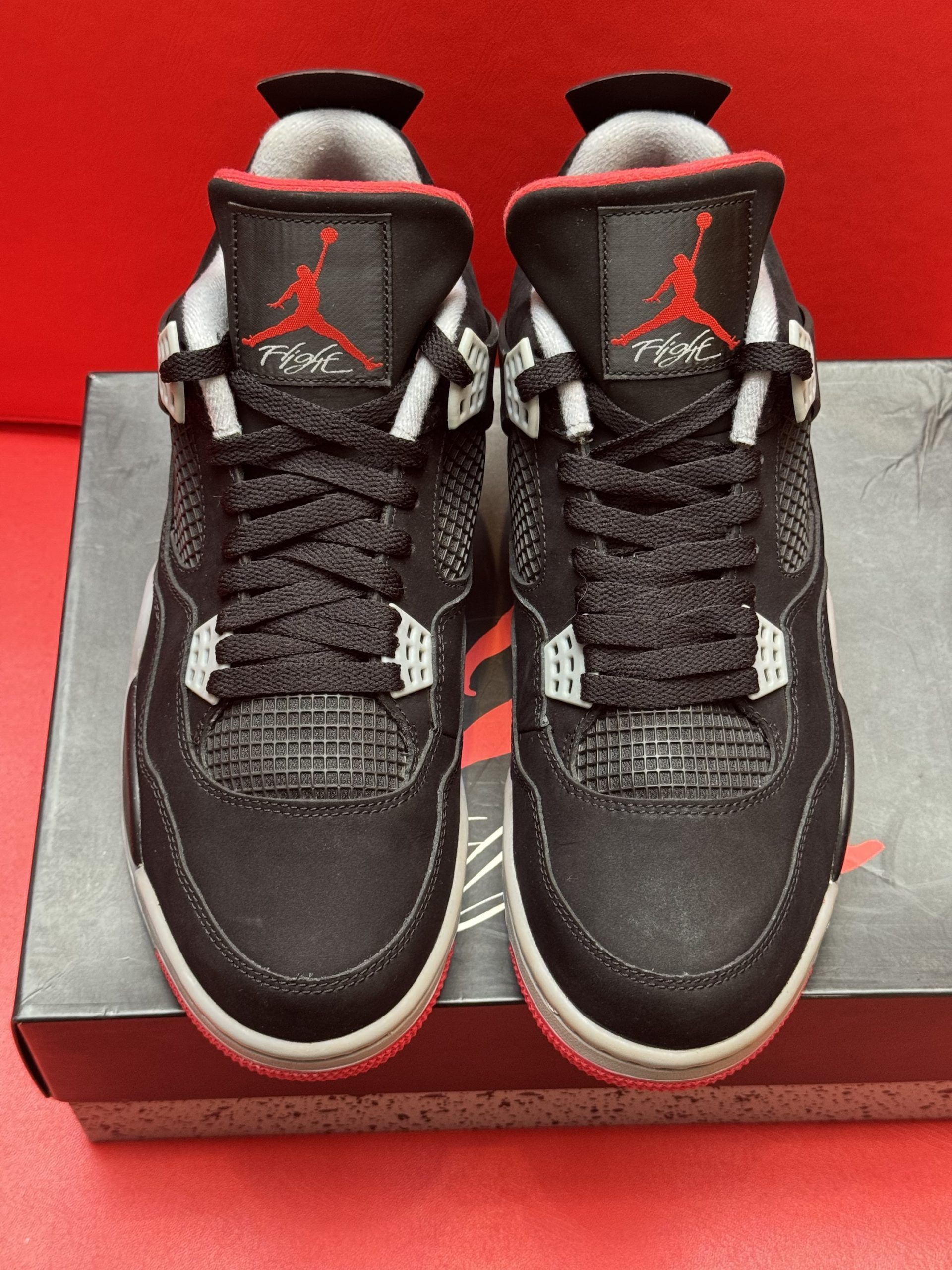 Black and red Air Jordan 4 sneakers on a box, sole visible.