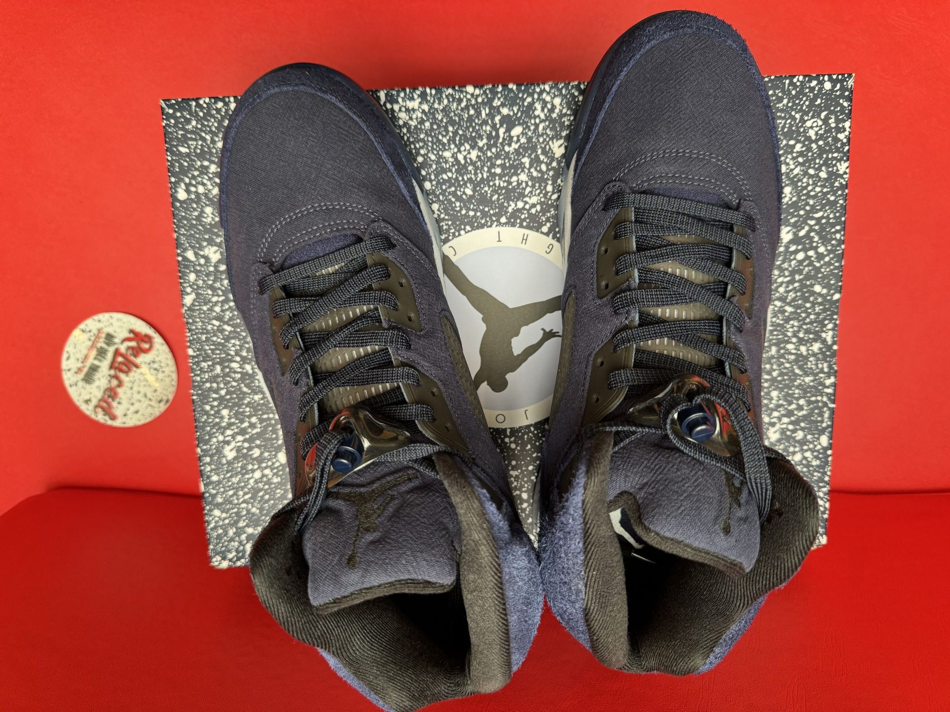 Blue and gray Air Jordan 5 sneakers on a speckled box, showing the sole with the Jumpman logo.