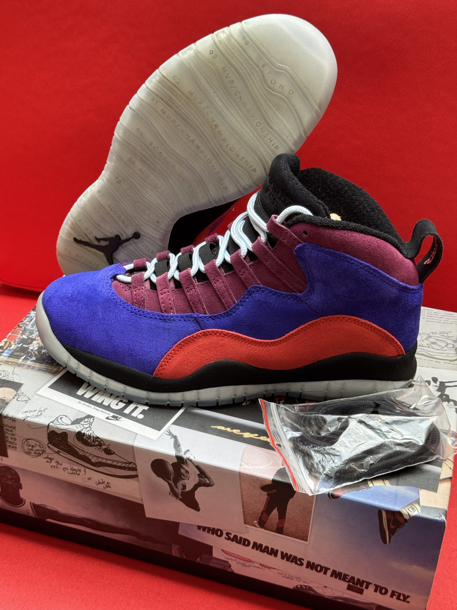 Air Jordan 10 sneakers on top of a shoebox. Purple, red, black, and white shoe with a clear sole.