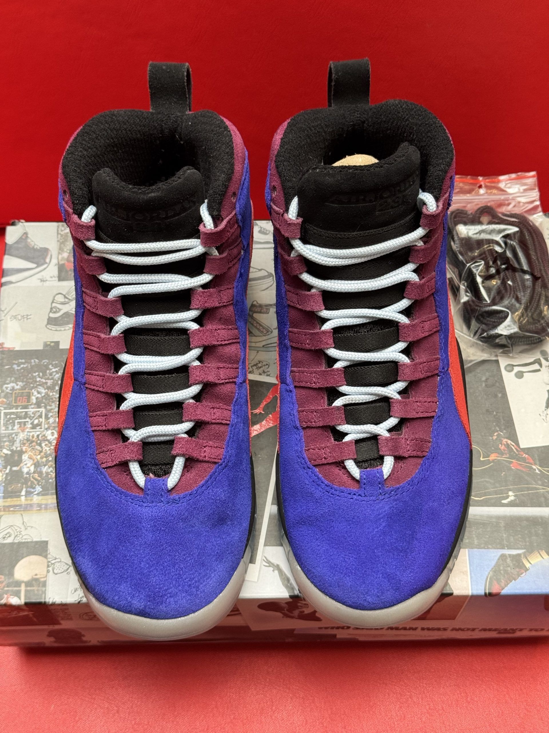 Air Jordan 10 sneakers on top of a shoebox. Purple, red, black, and white shoe with a clear sole.