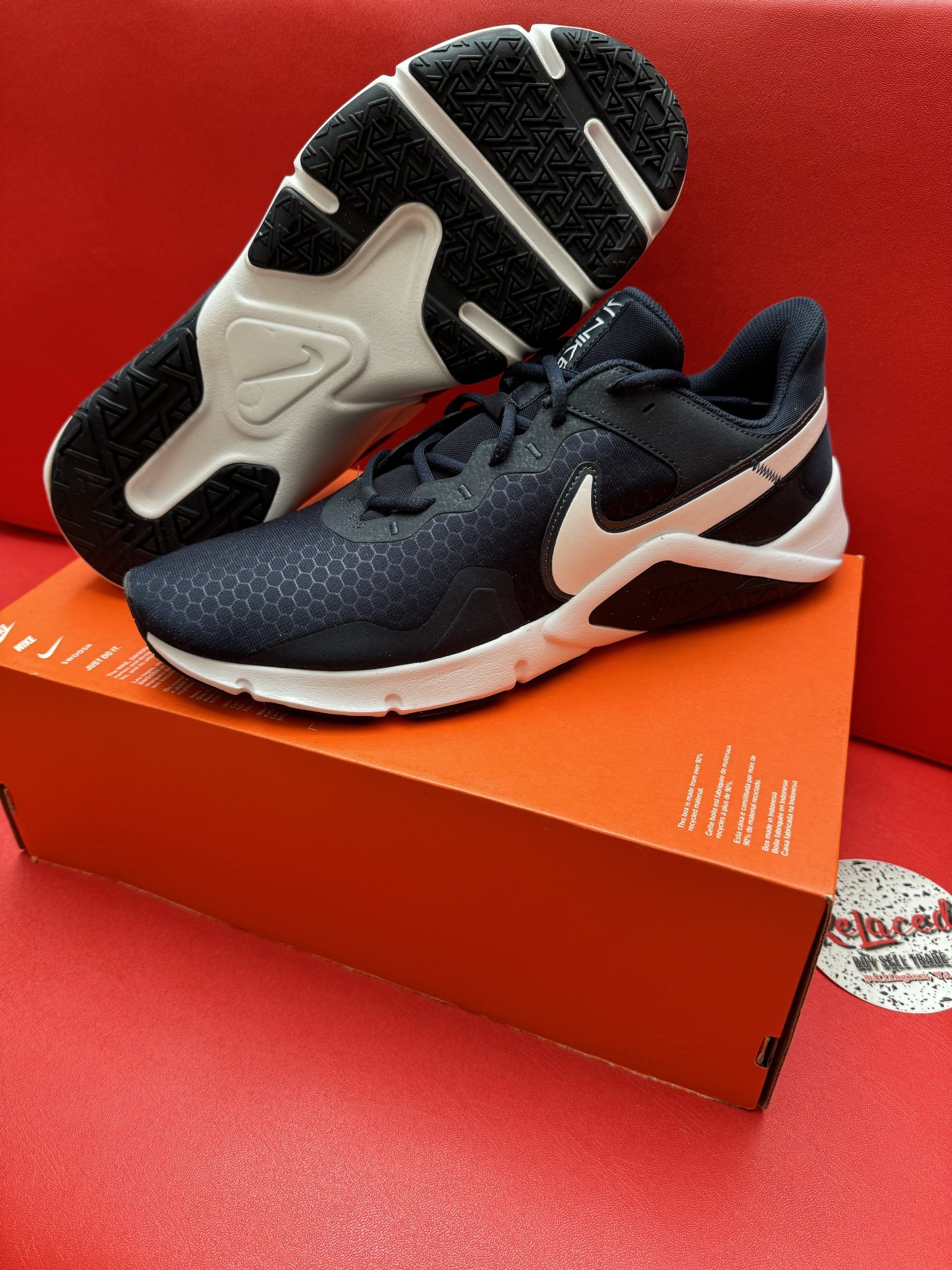 Navy blue Nike sneakers on orange shoe box; white swoosh and sole.