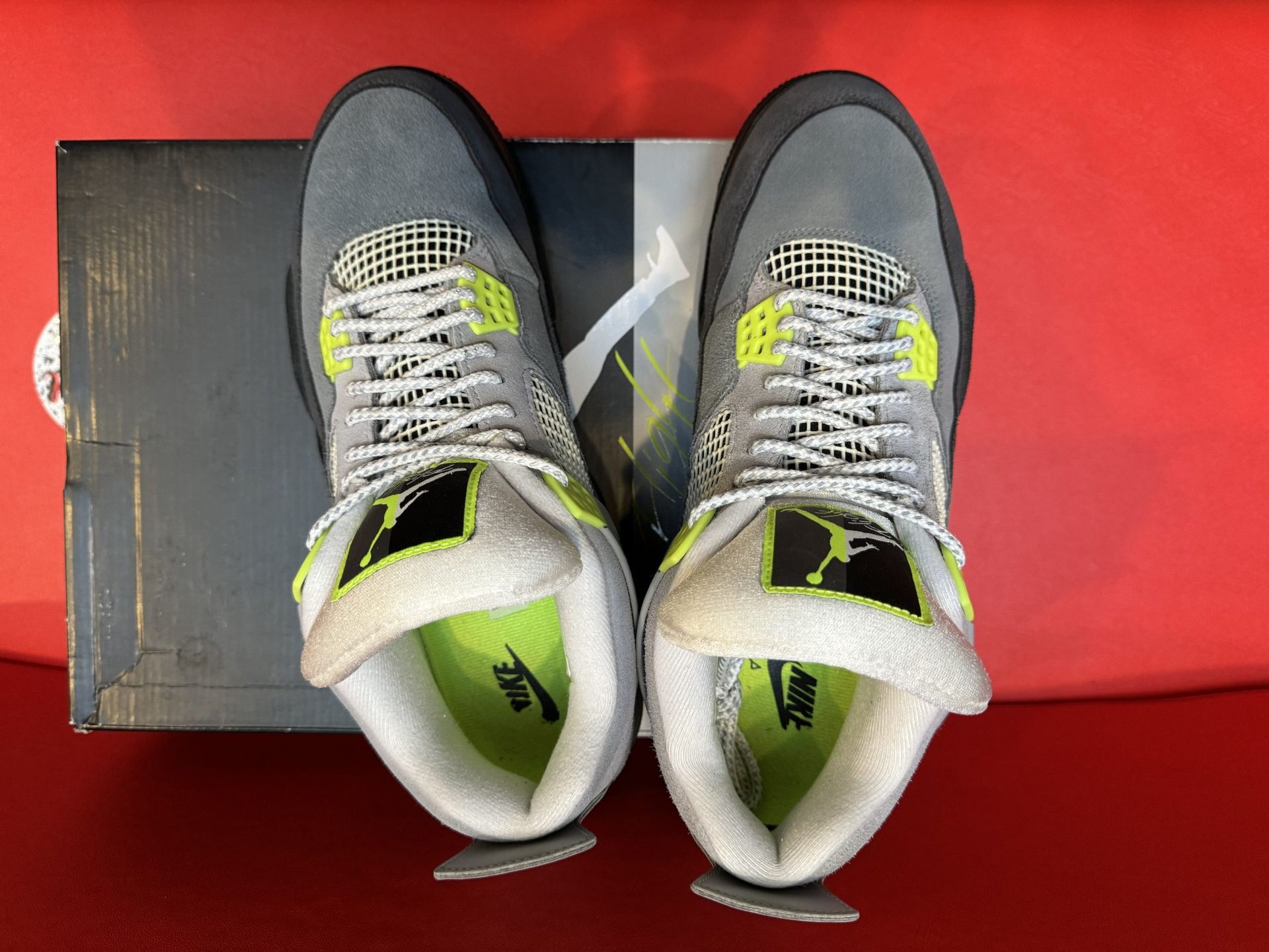 Gray and black Air Jordan 4 sneakers with yellow accents, displayed on a shoebox.