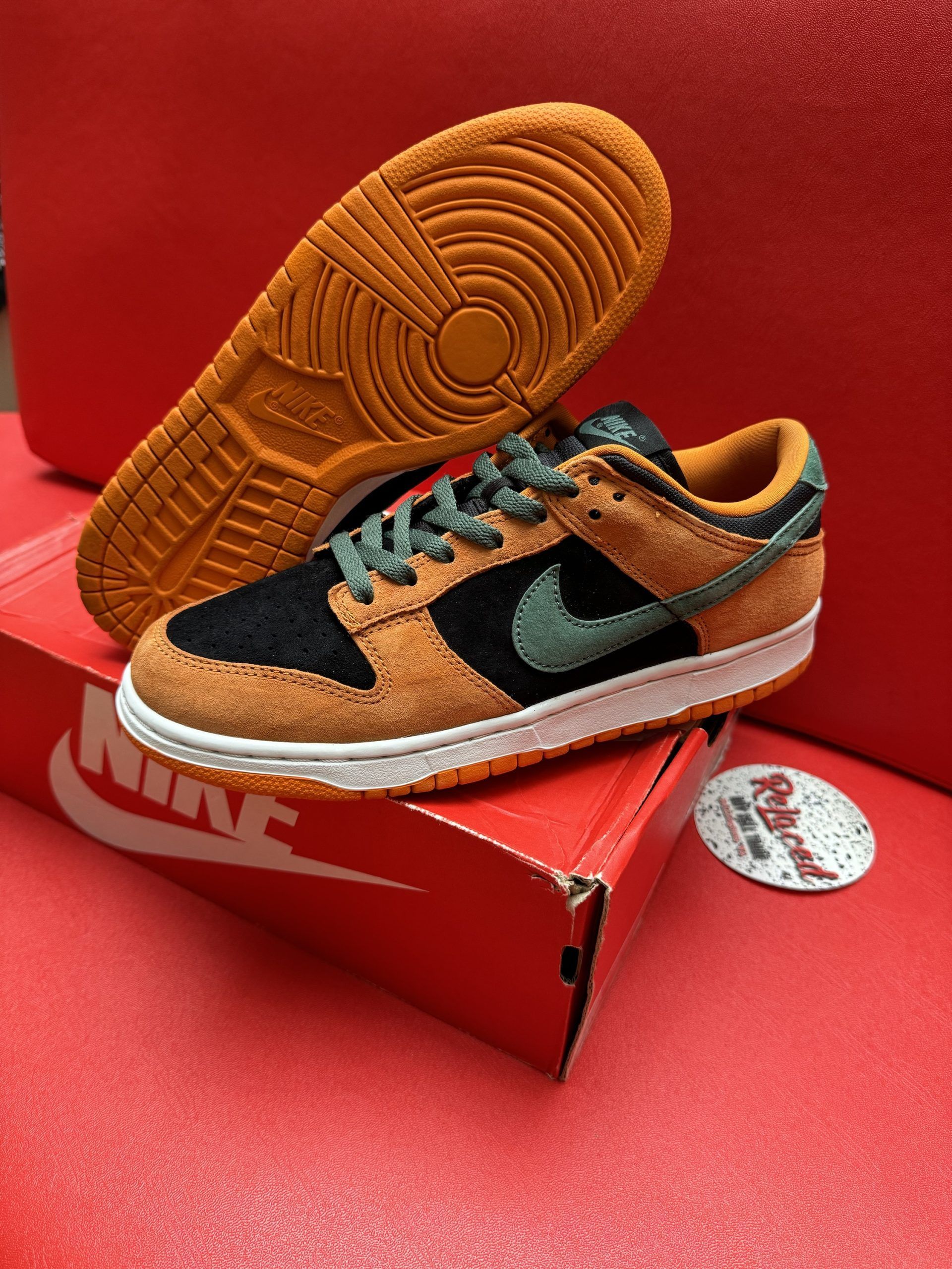 Nike Dunk Low sneakers, brown, black, and teal, on red Nike box. Orange sole visible.