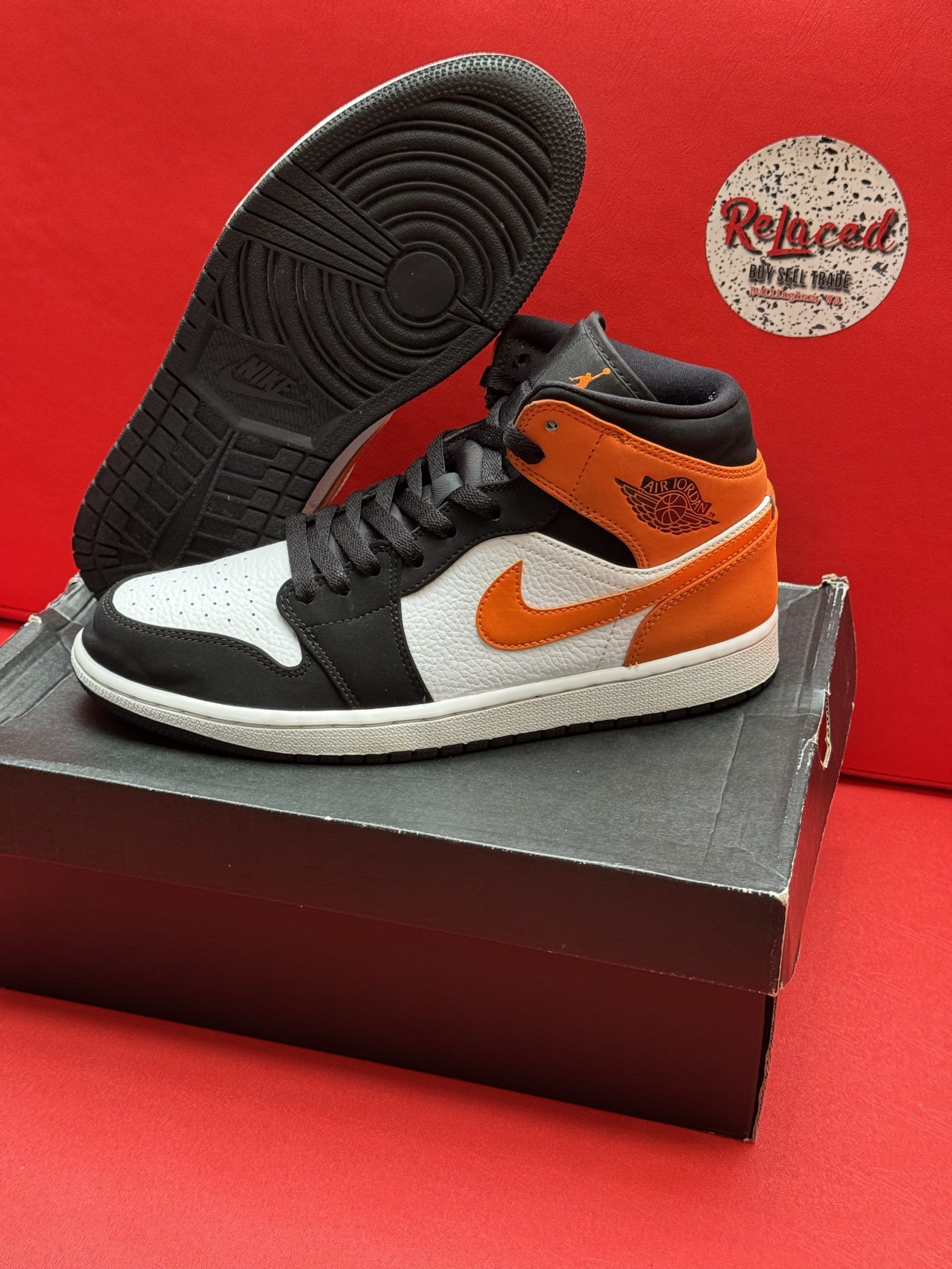 Orange and black Air Jordan sneaker on a black box, with the sole visible.