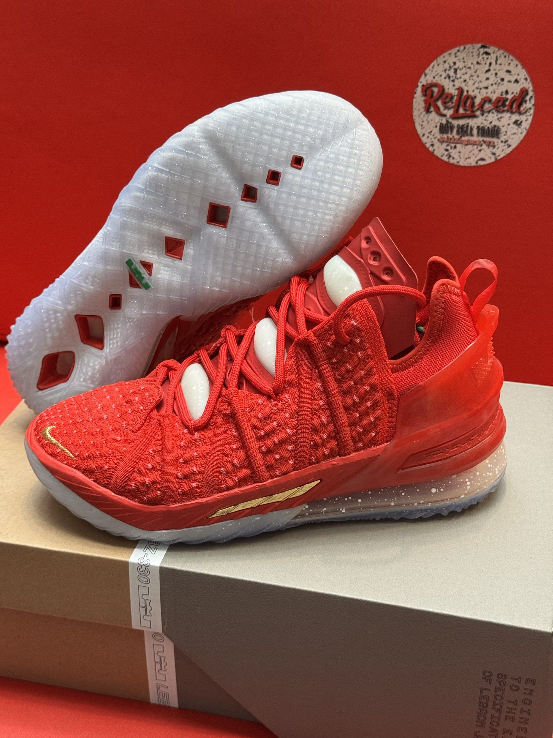 Red Nike LeBron 18 basketball sneakers with white soles, placed atop a shoebox.