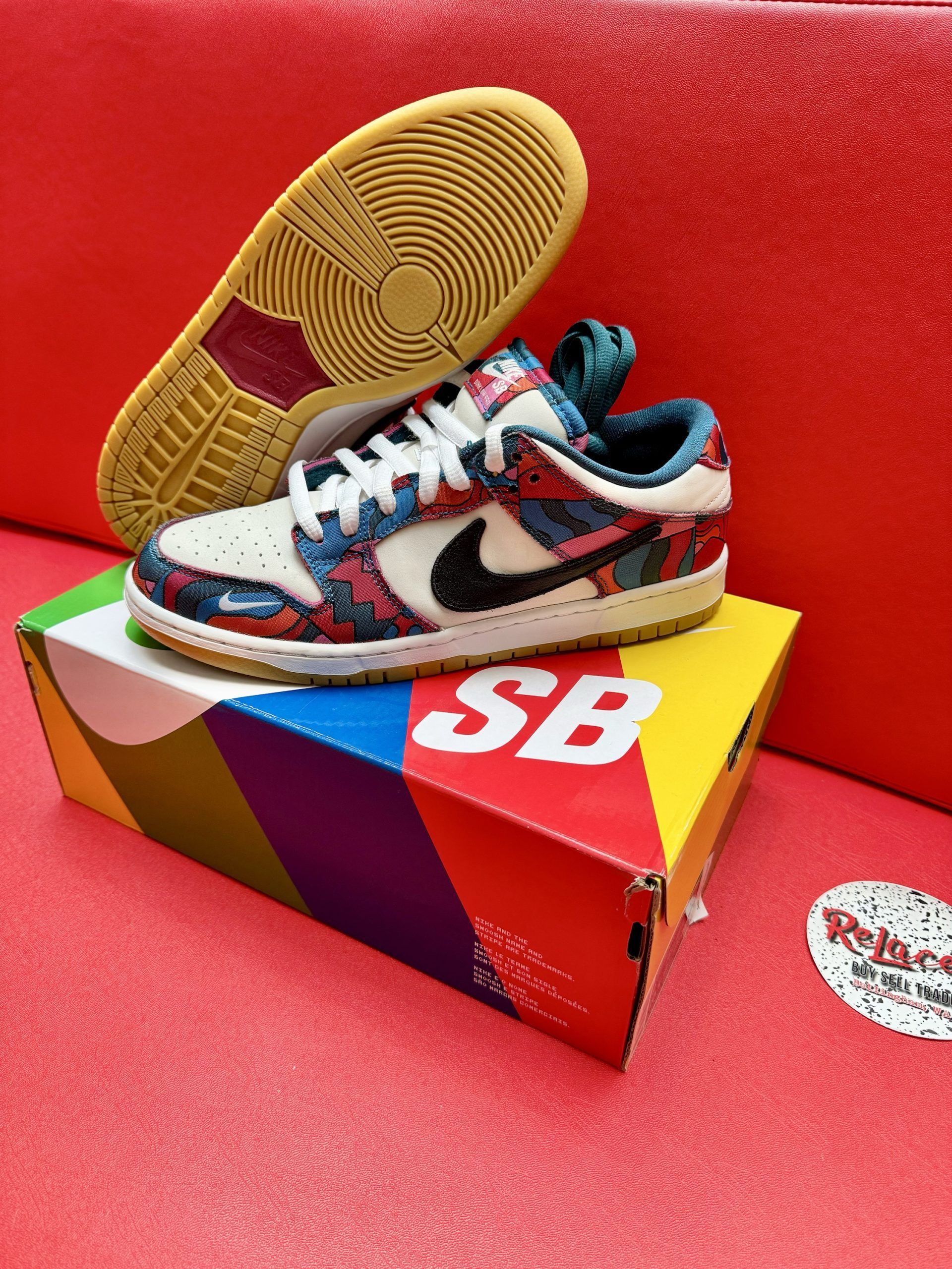 Nike SB Dunk sneaker with colorful floral pattern and black Swoosh on box.