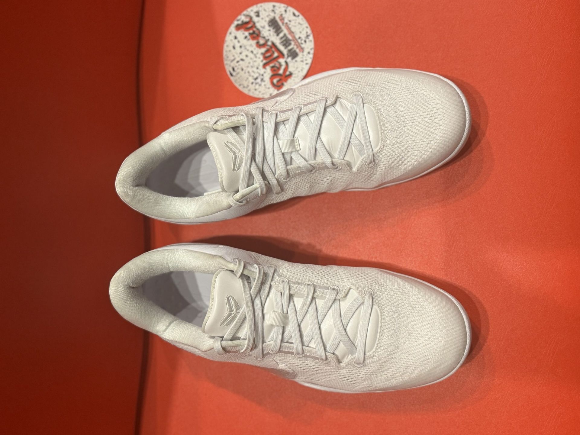 White Nike sneakers on a red surface, sole facing up.