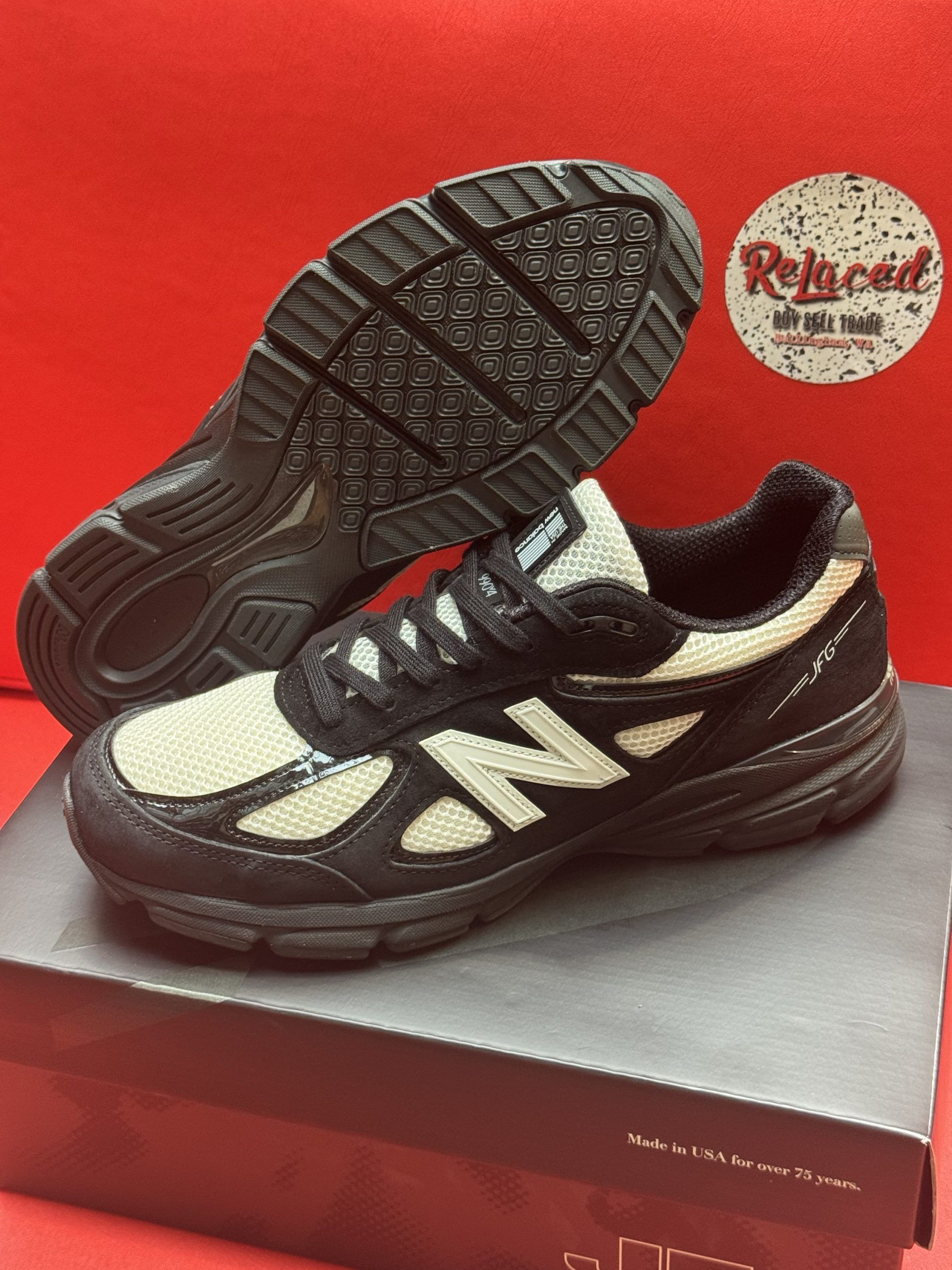 Black and cream New Balance sneakers on a black box, sole visible.