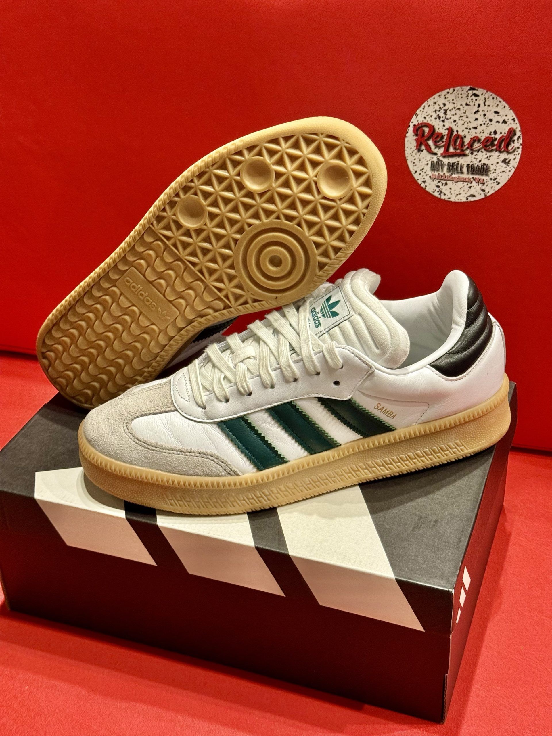 Adidas Samba sneakers with green stripes and gum sole, atop a shoebox, with one shoe’s sole displayed.
