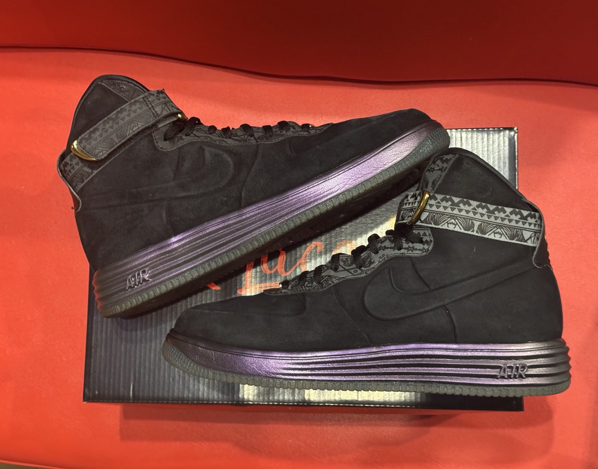 Black and purple Nike Air Force 1 Lunar sneakers with a high top, resting on a shoebox.
