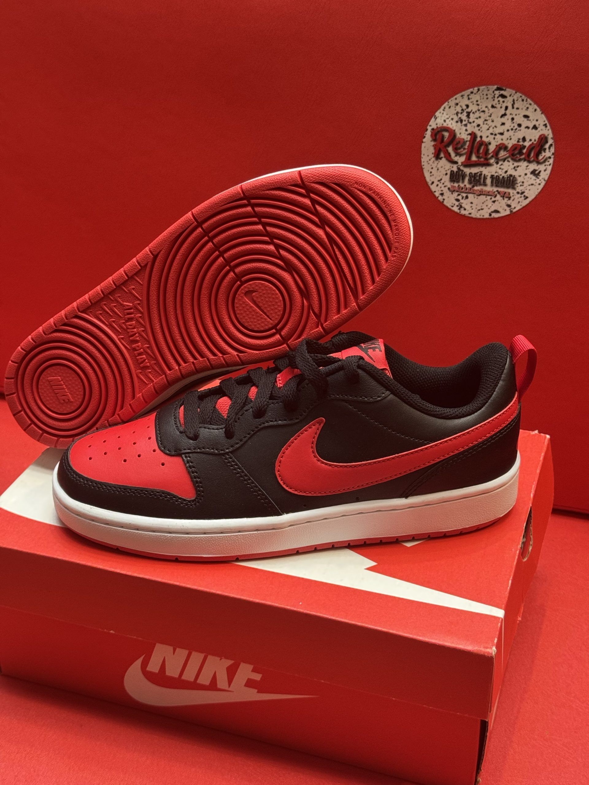 Black and red Nike sneakers on a red and white box; the sole is visible.