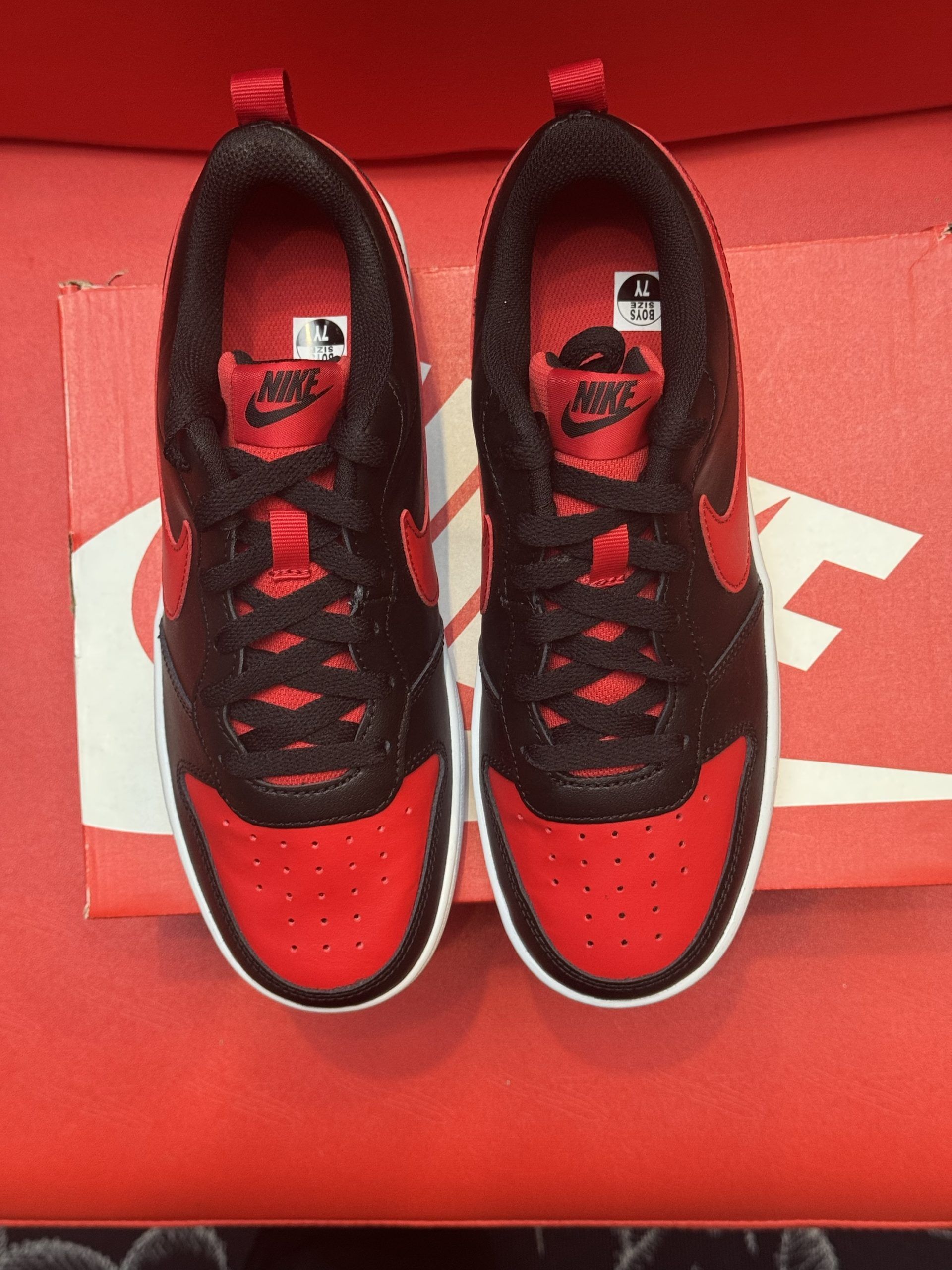 Black and red Nike sneakers on a red and white box; the sole is visible.