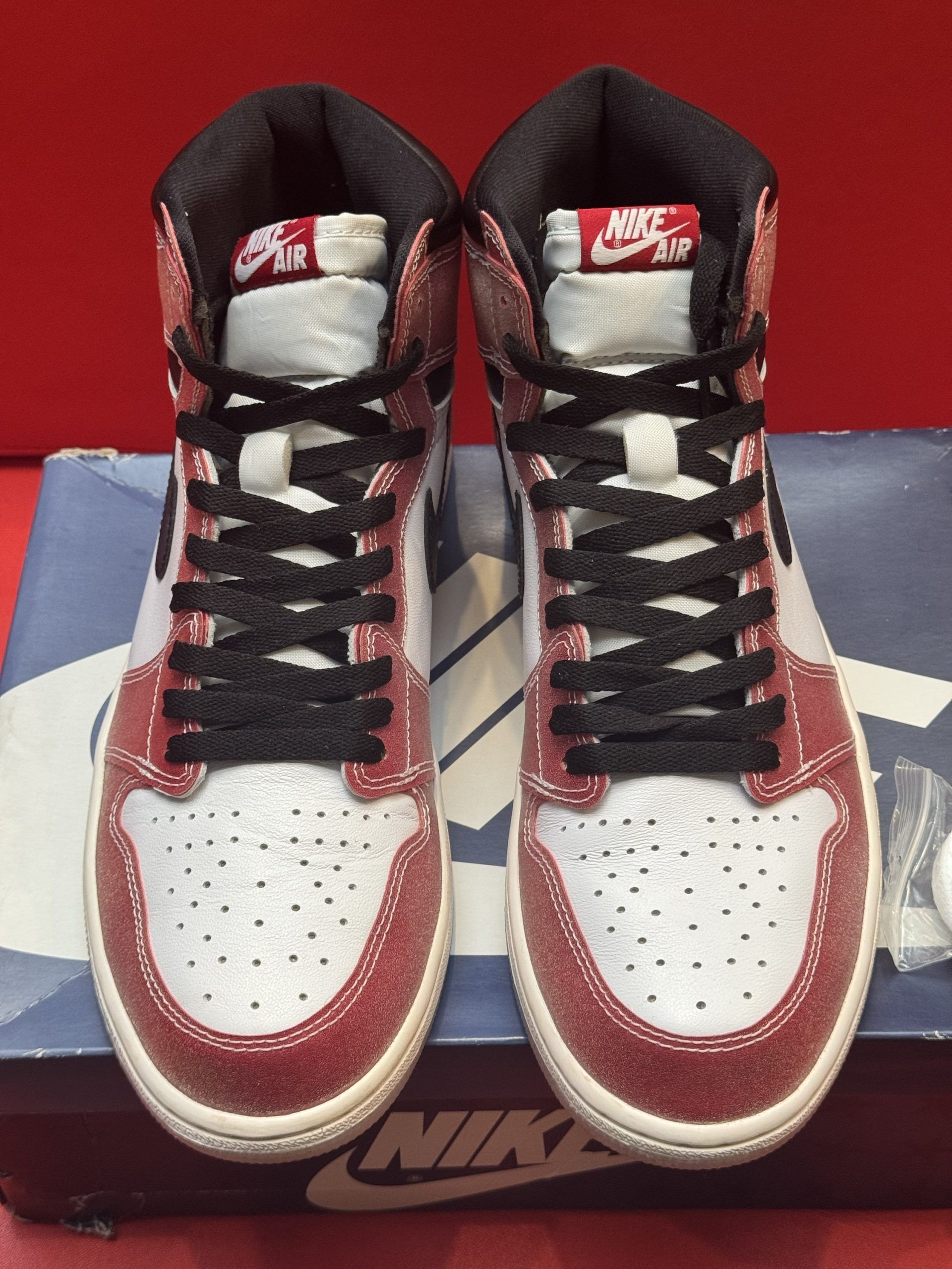 Air Jordan 1 sneaker with white, red, and black accents, sitting on a blue Nike shoebox.