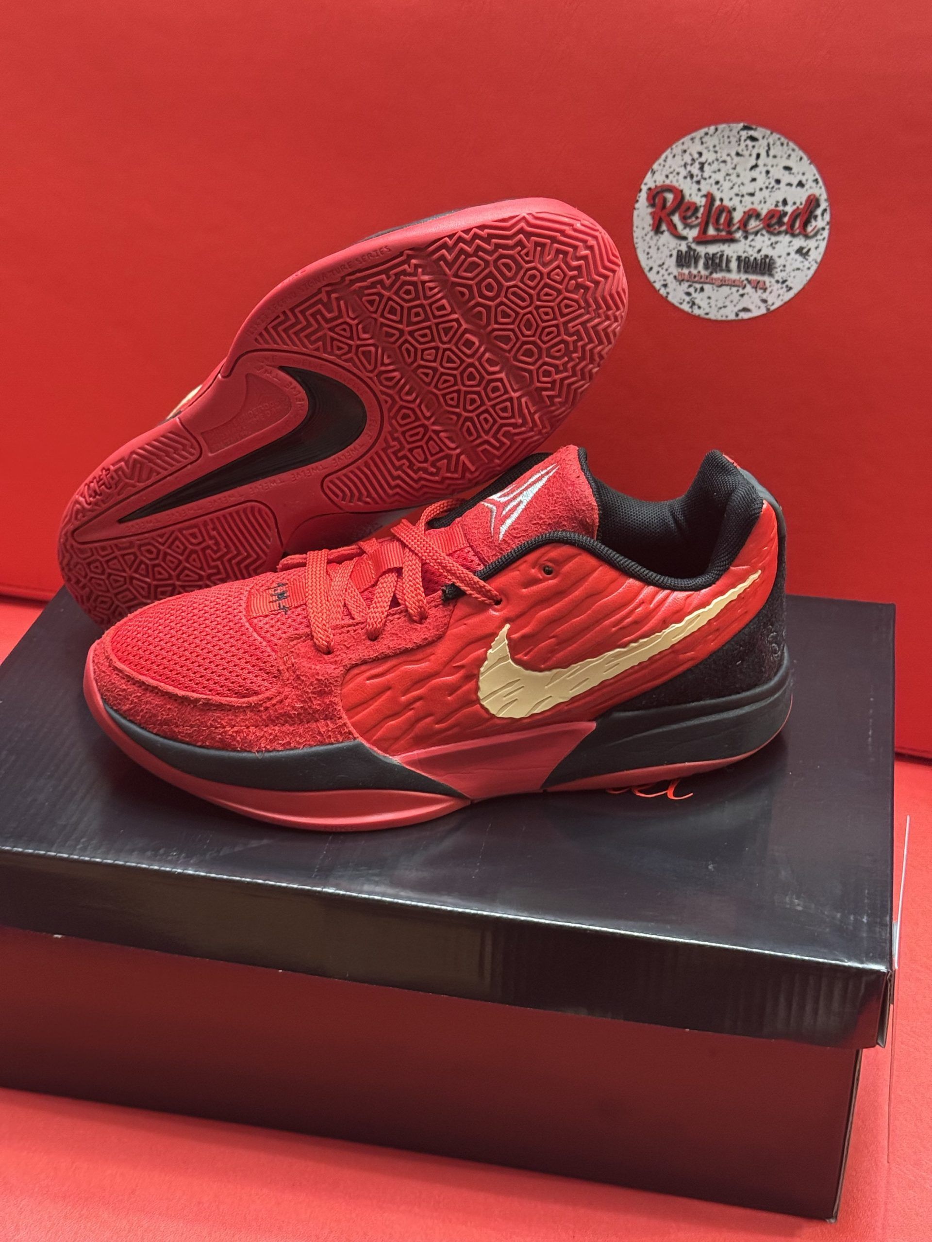 Red and gold Nike basketball shoe on a black box, sole visible.