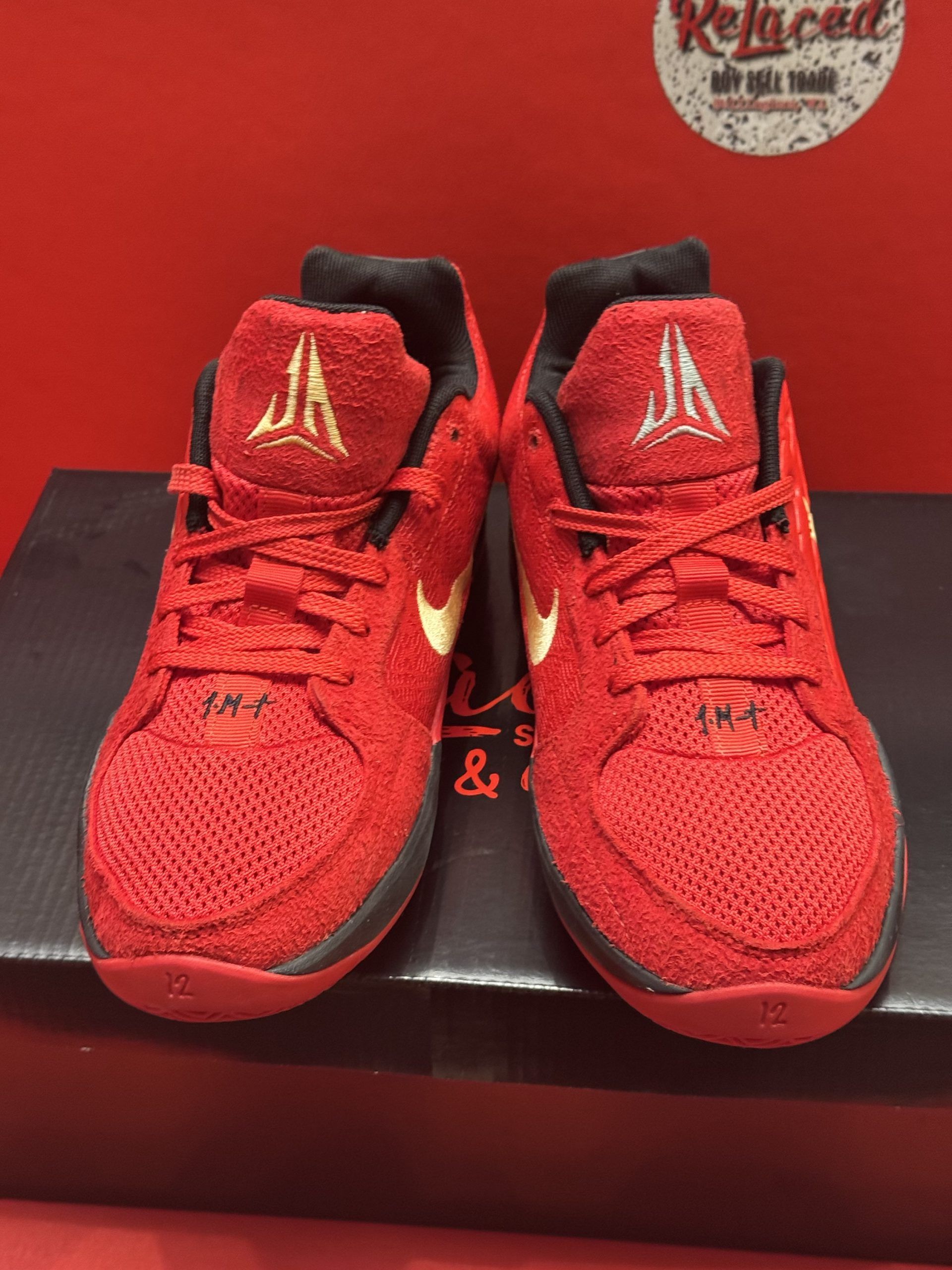 Red and gold Nike basketball shoe on a black box, sole visible.