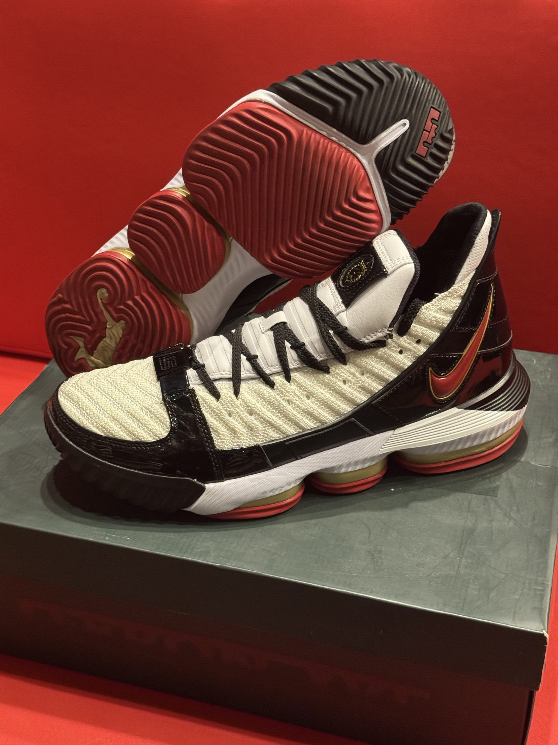 Nike LeBron 16 basketball shoe with a red, white, and black color scheme, resting on a shoebox.