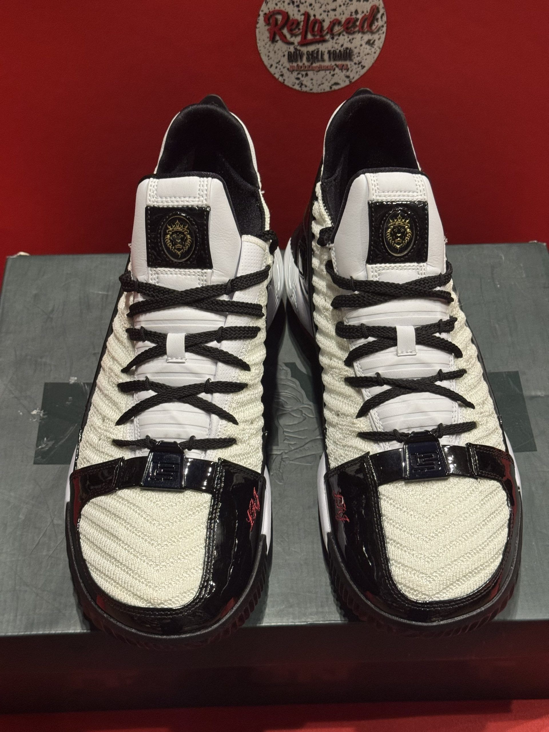 Nike LeBron 16 basketball shoe with a red, white, and black color scheme, resting on a shoebox.