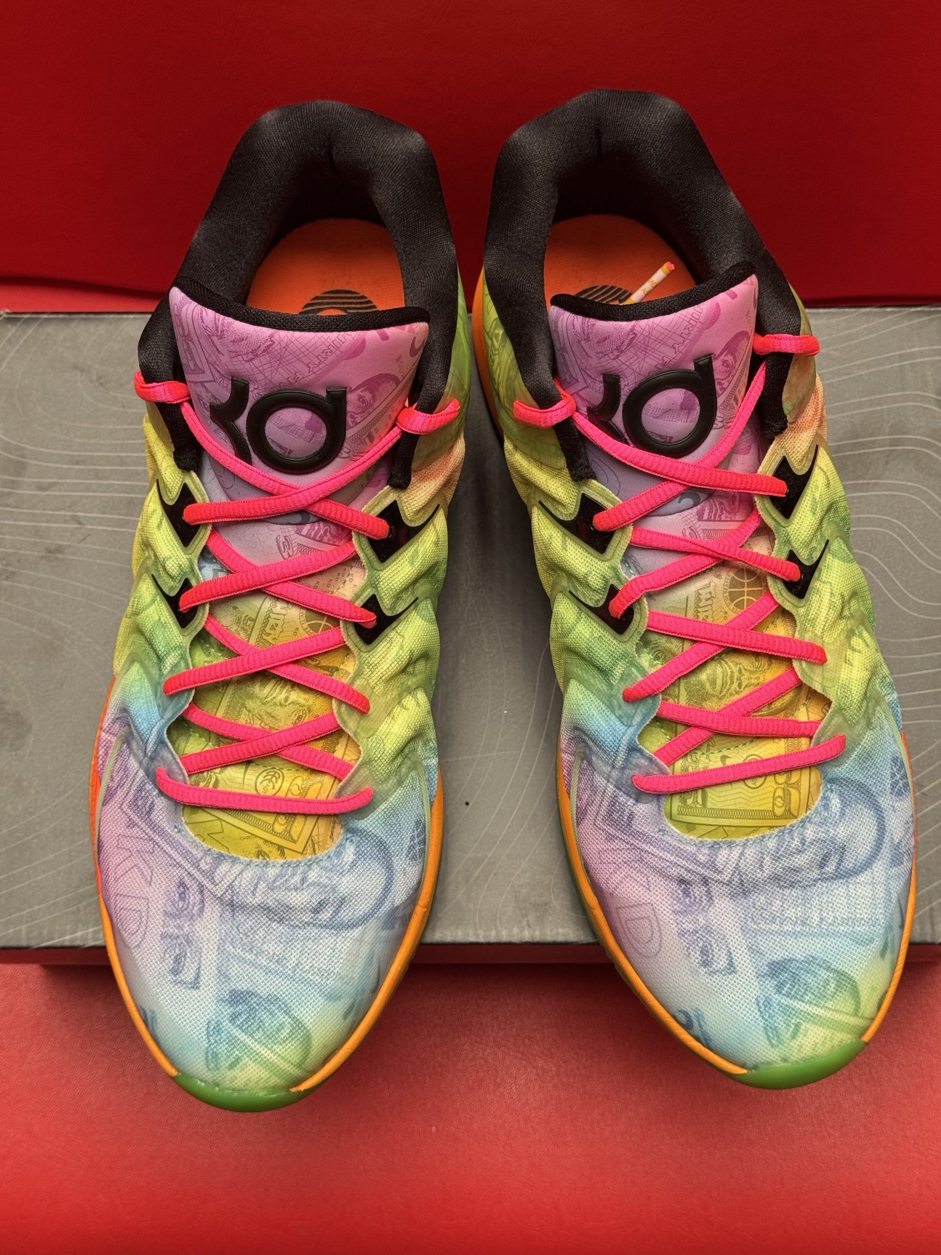 Colorful Nike basketball shoes with swirling patterns and neon accents, resting on a box.