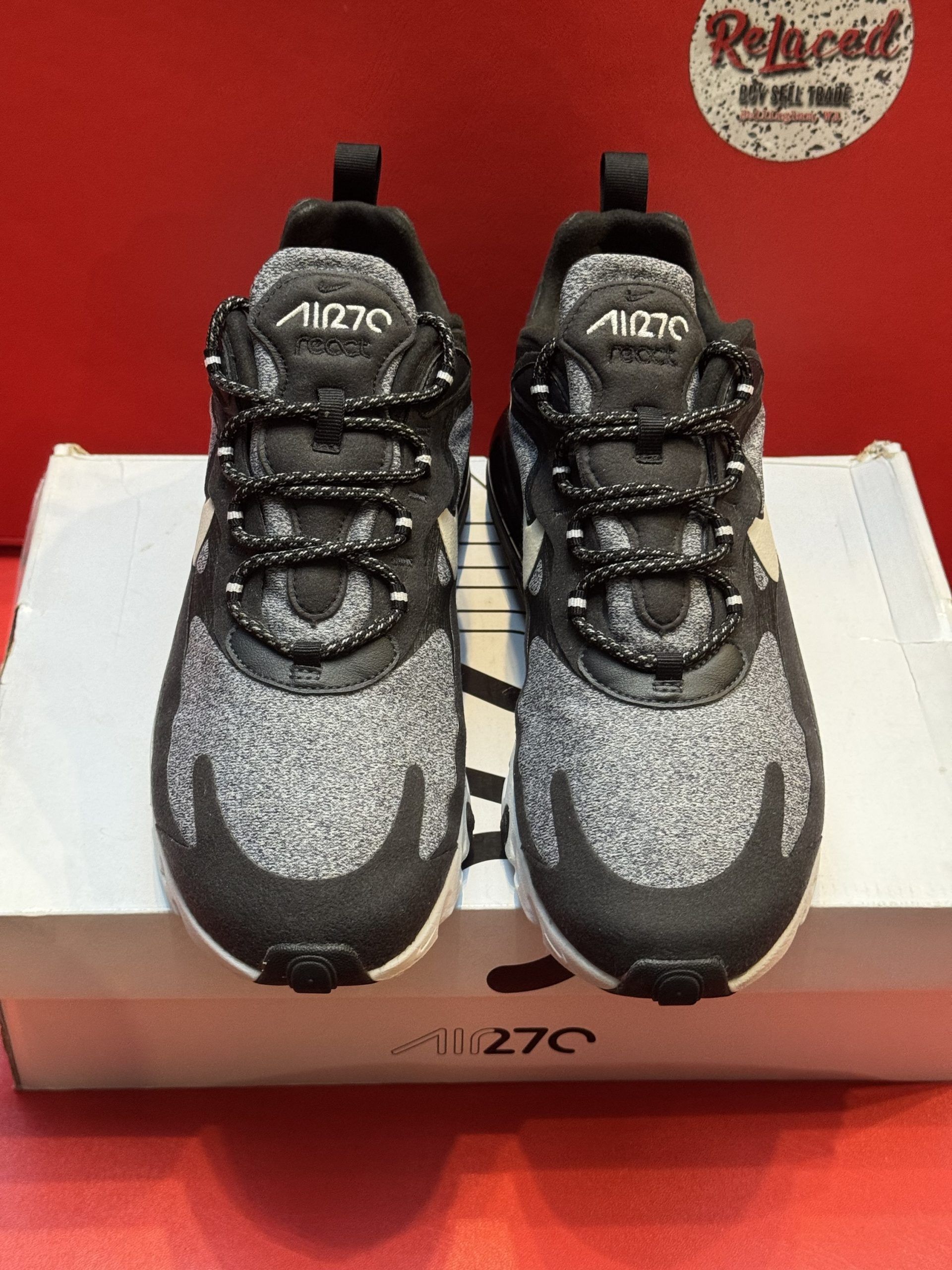 Black and gray Nike Air Max 270 sneakers on a white box, with white swoosh, and a textured black and white sole.