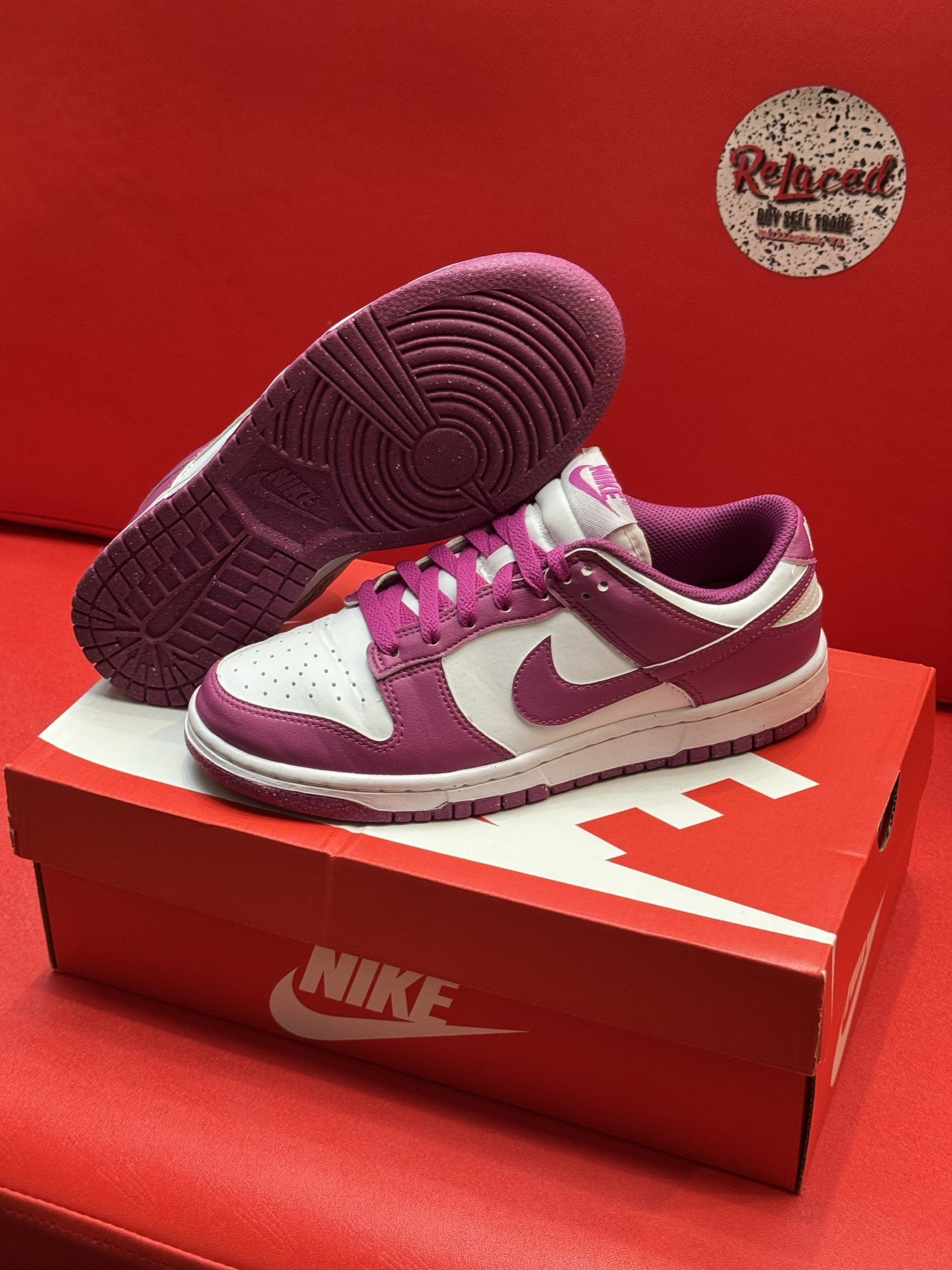 Nike Dunk Low sneakers in white and purple, displayed on a red Nike shoebox.
