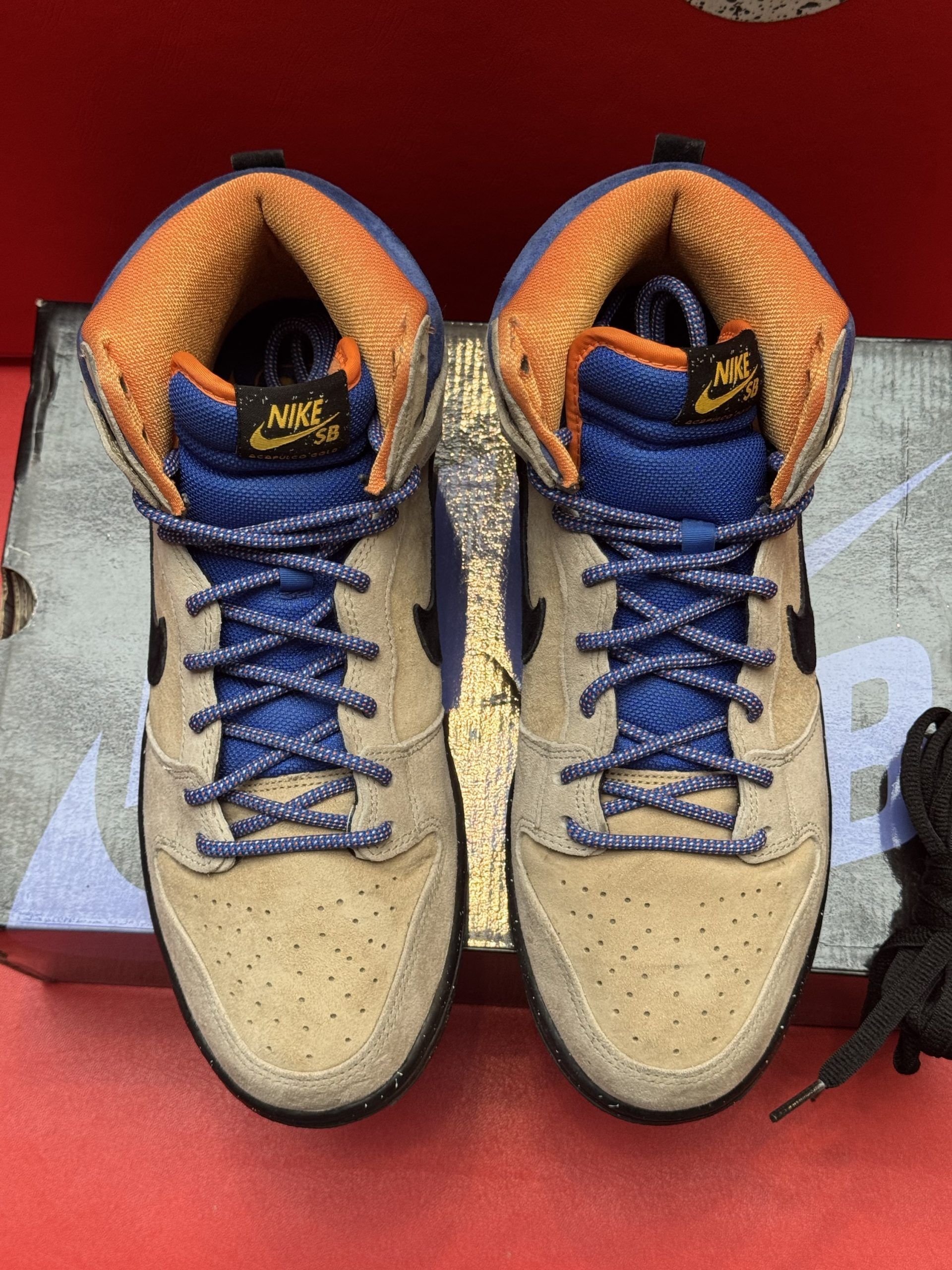 Nike Dunk high-top sneaker in tan, black, and blue. Black sole with orange accents. 