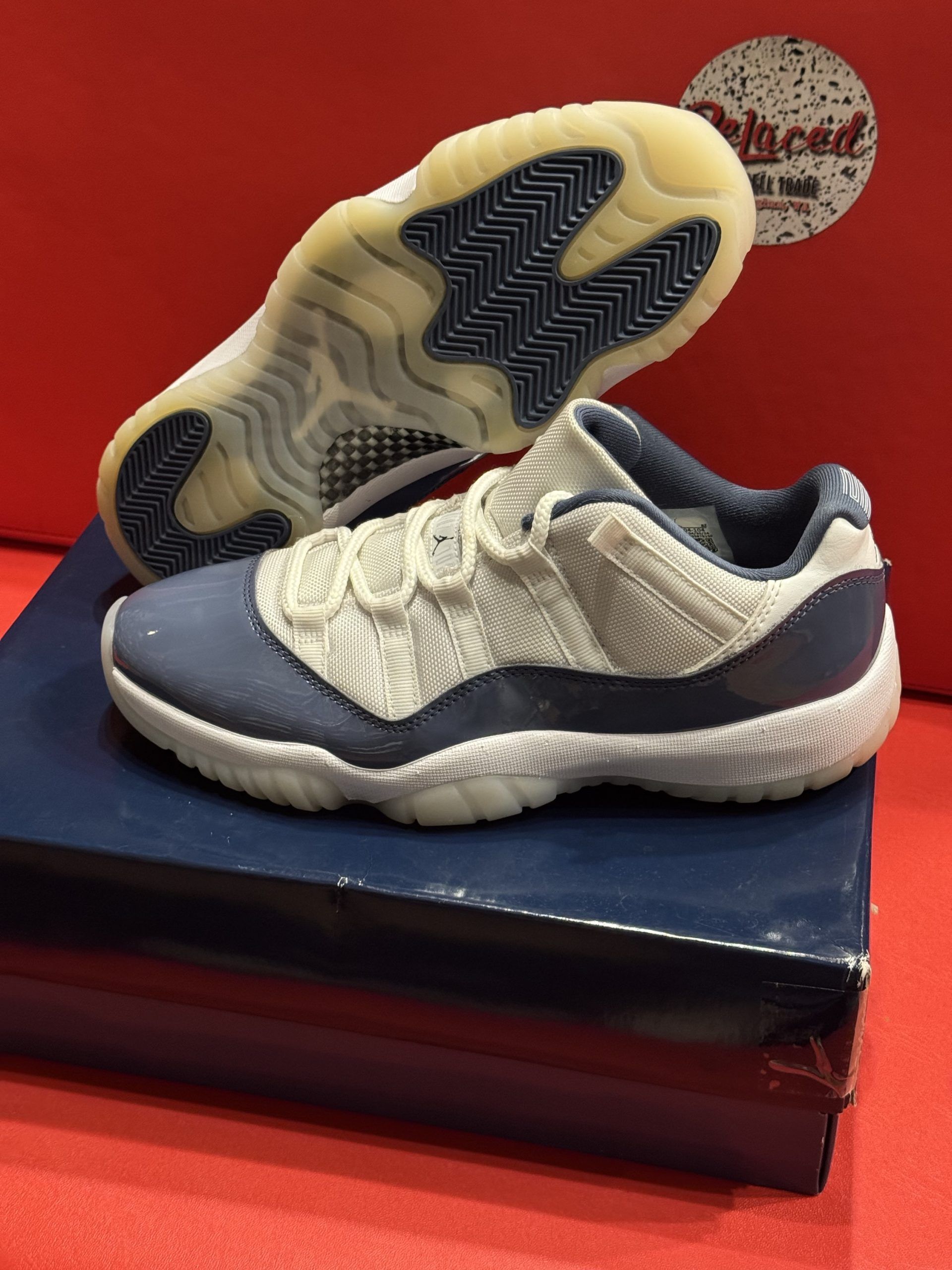 Blue and white Air Jordan sneakers on top of a blue shoebox, red background.