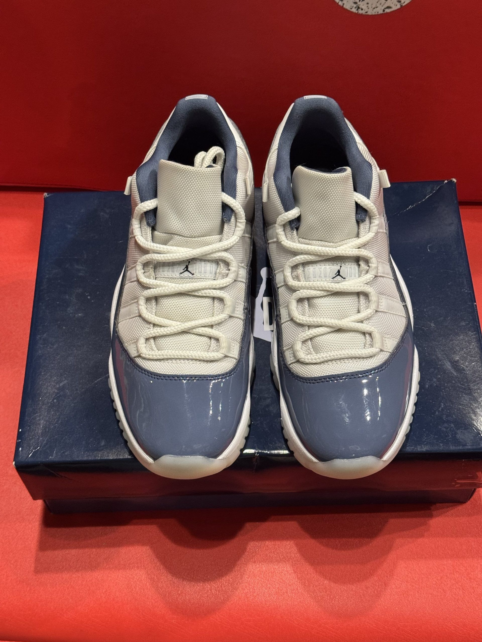 Blue and white Air Jordan sneakers on top of a blue shoebox, red background.