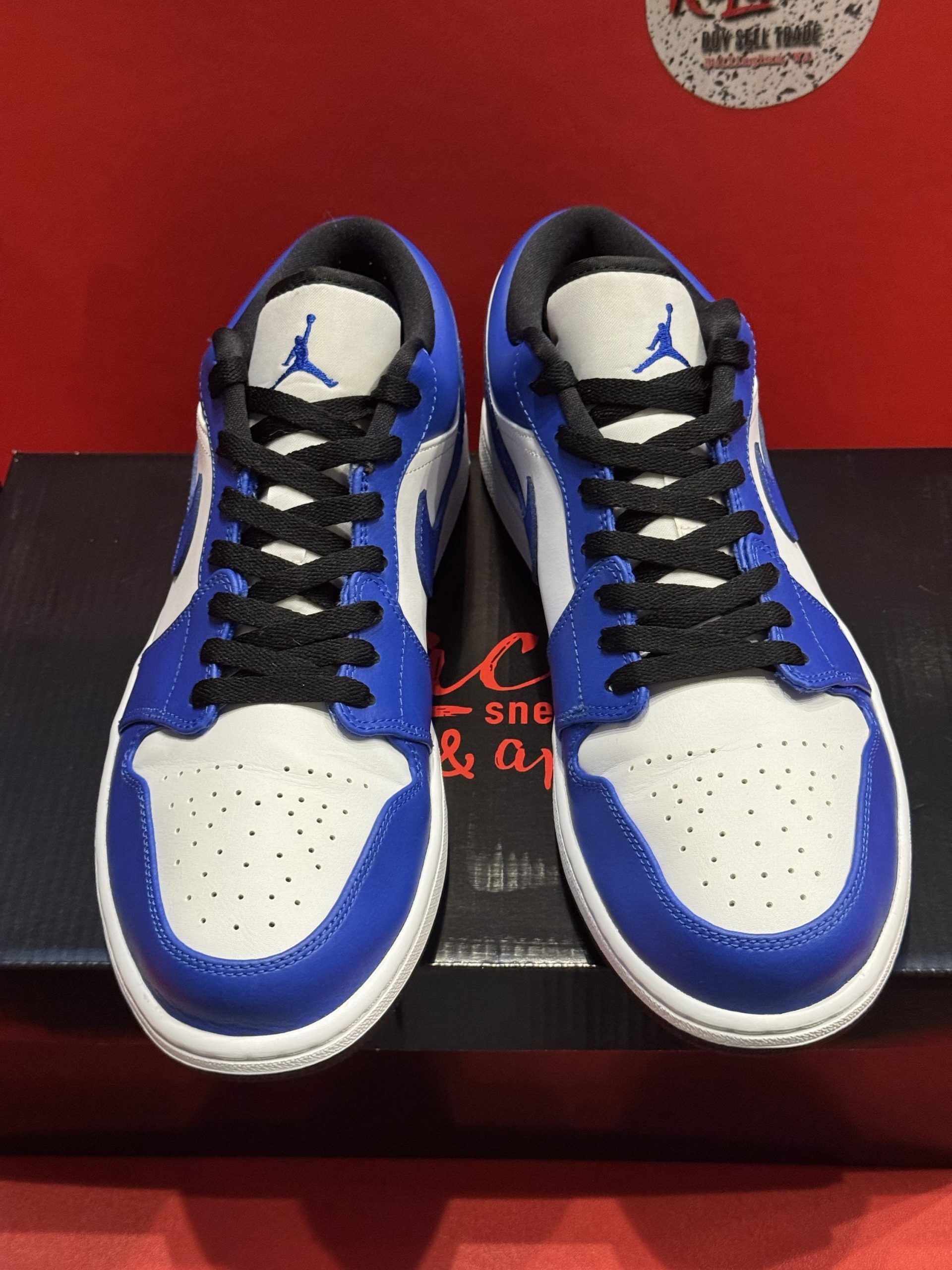 Blue and white Air Jordan 1 Low sneaker on a black box, sole visible.
