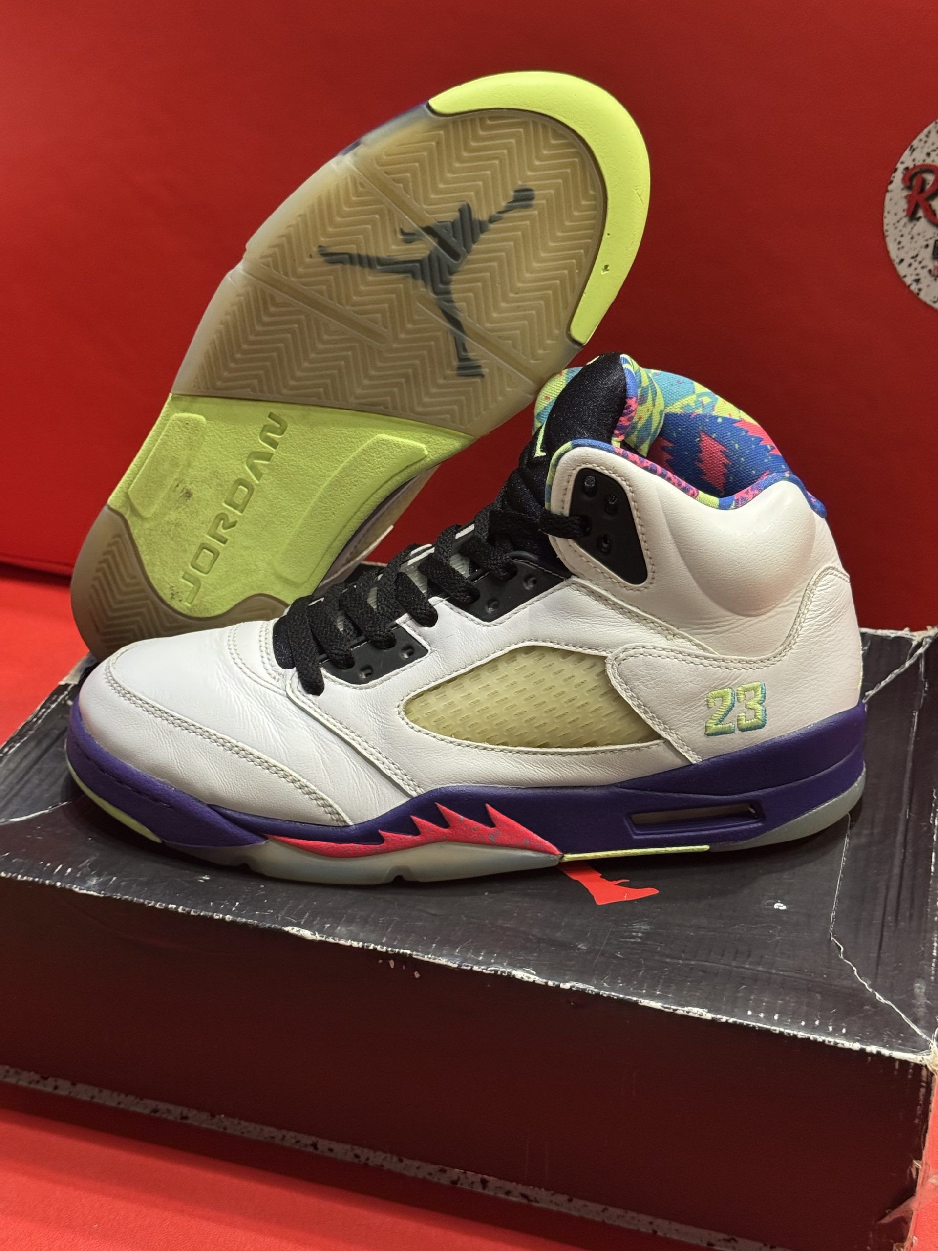 Air Jordan 5 sneaker, white, purple and pink accents, with multi-colored interior, sitting on shoe box.