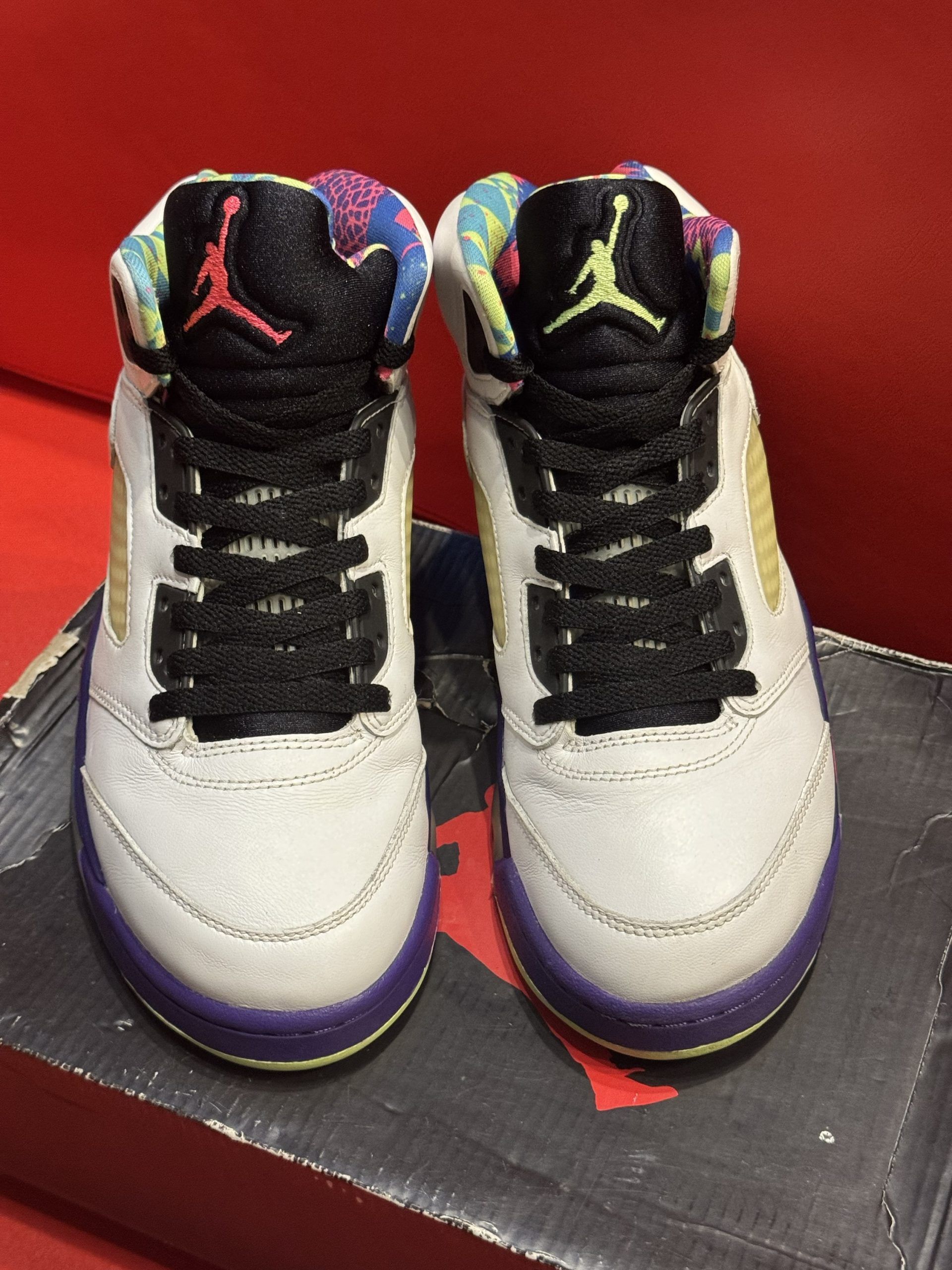 Air Jordan 5 sneaker, white, purple and pink accents, with multi-colored interior, sitting on shoe box.