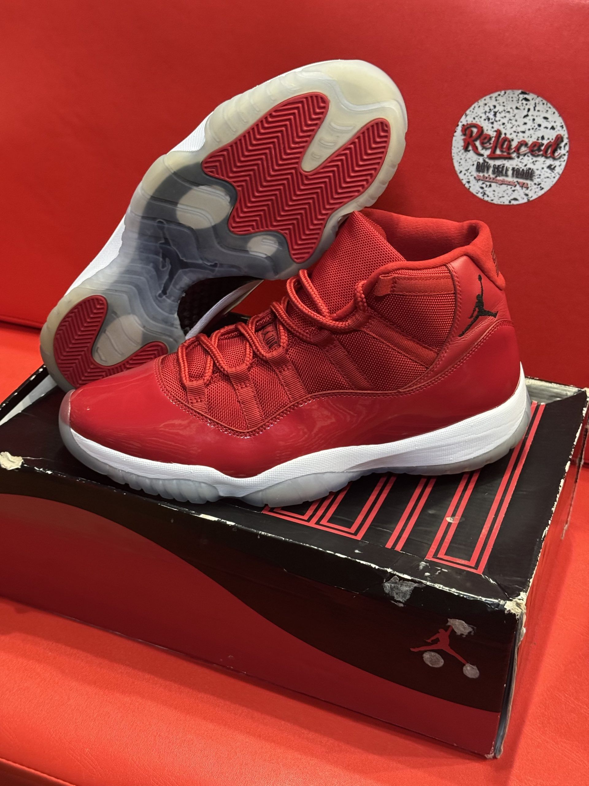 Red Air Jordan 11 sneakers on a box, with a white sole and red sole.