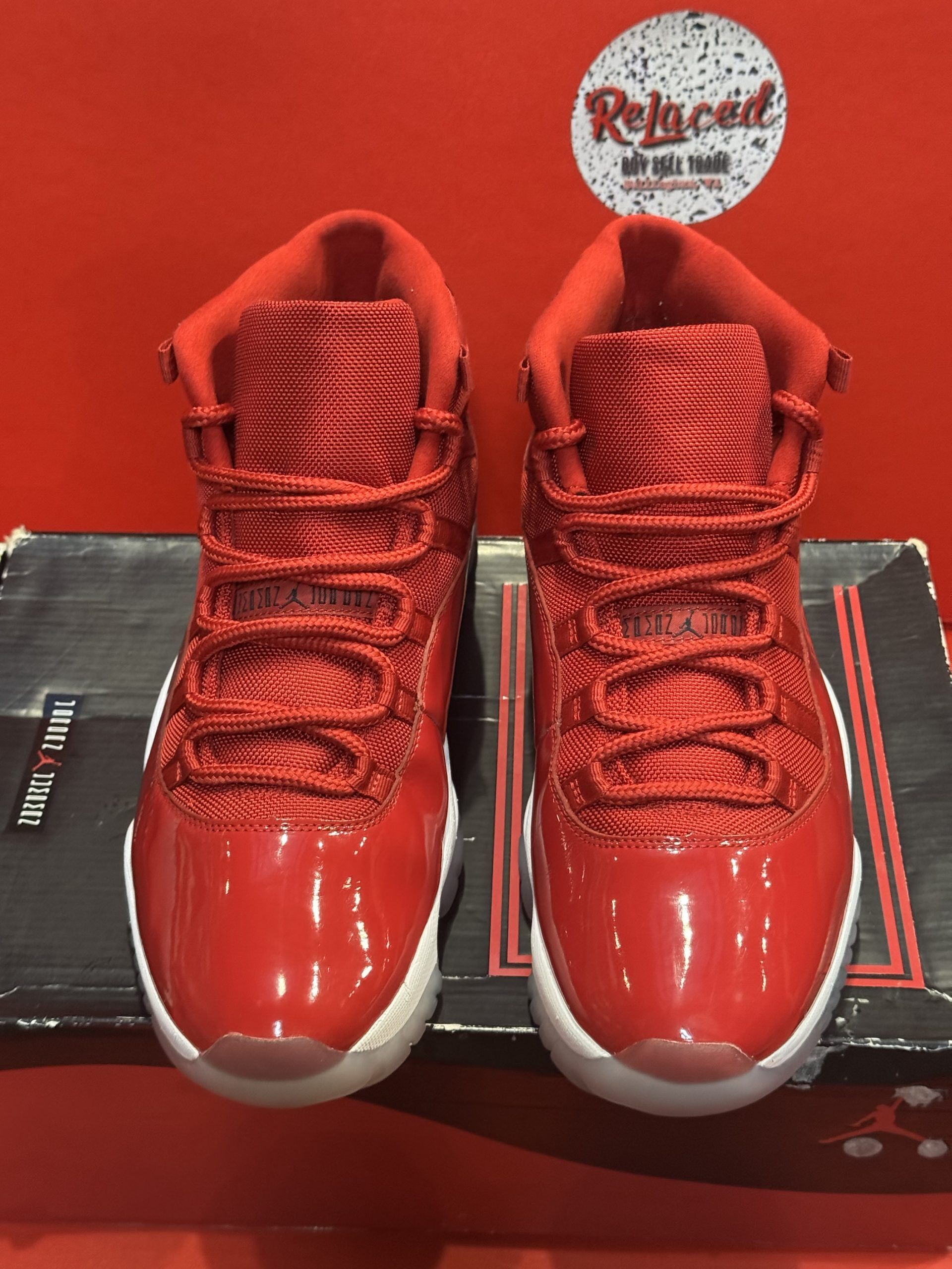 Red Air Jordan 11 sneakers on a box, with a white sole and red sole.
