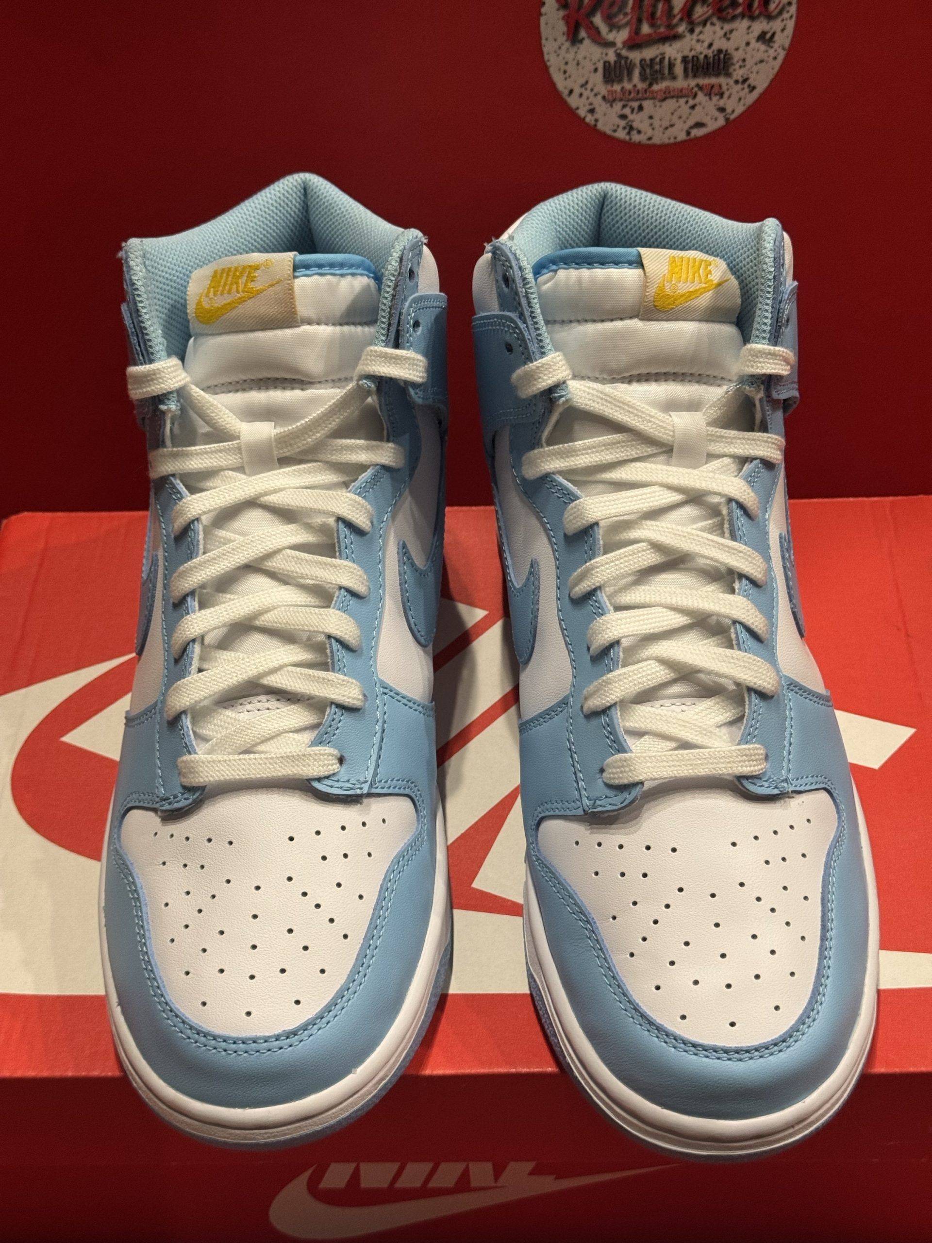 Blue and white Nike Dunk High sneakers on a red Nike box, light blue sole visible.