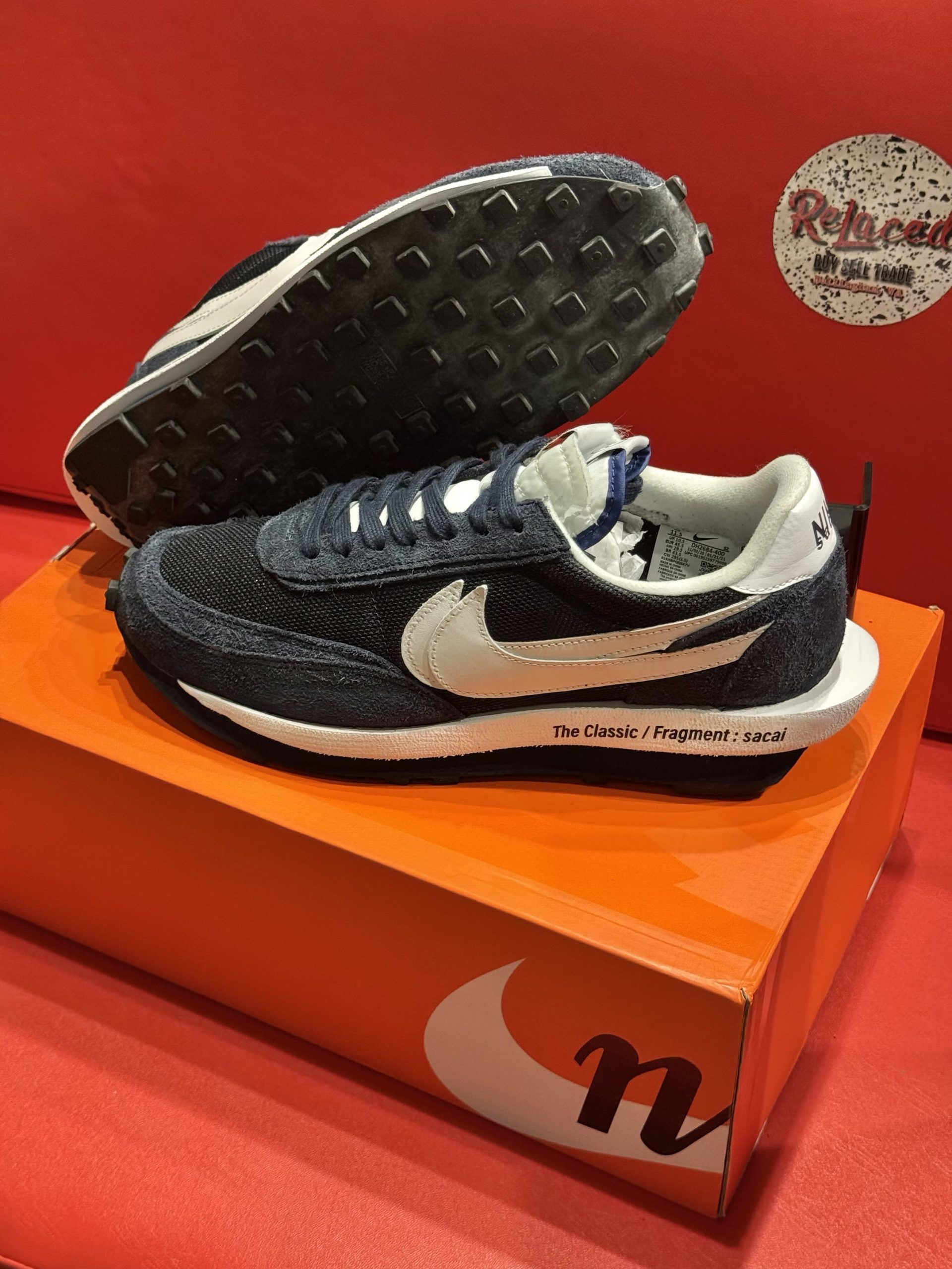 Nike sneakers, black and white, on an orange box, red backdrop.