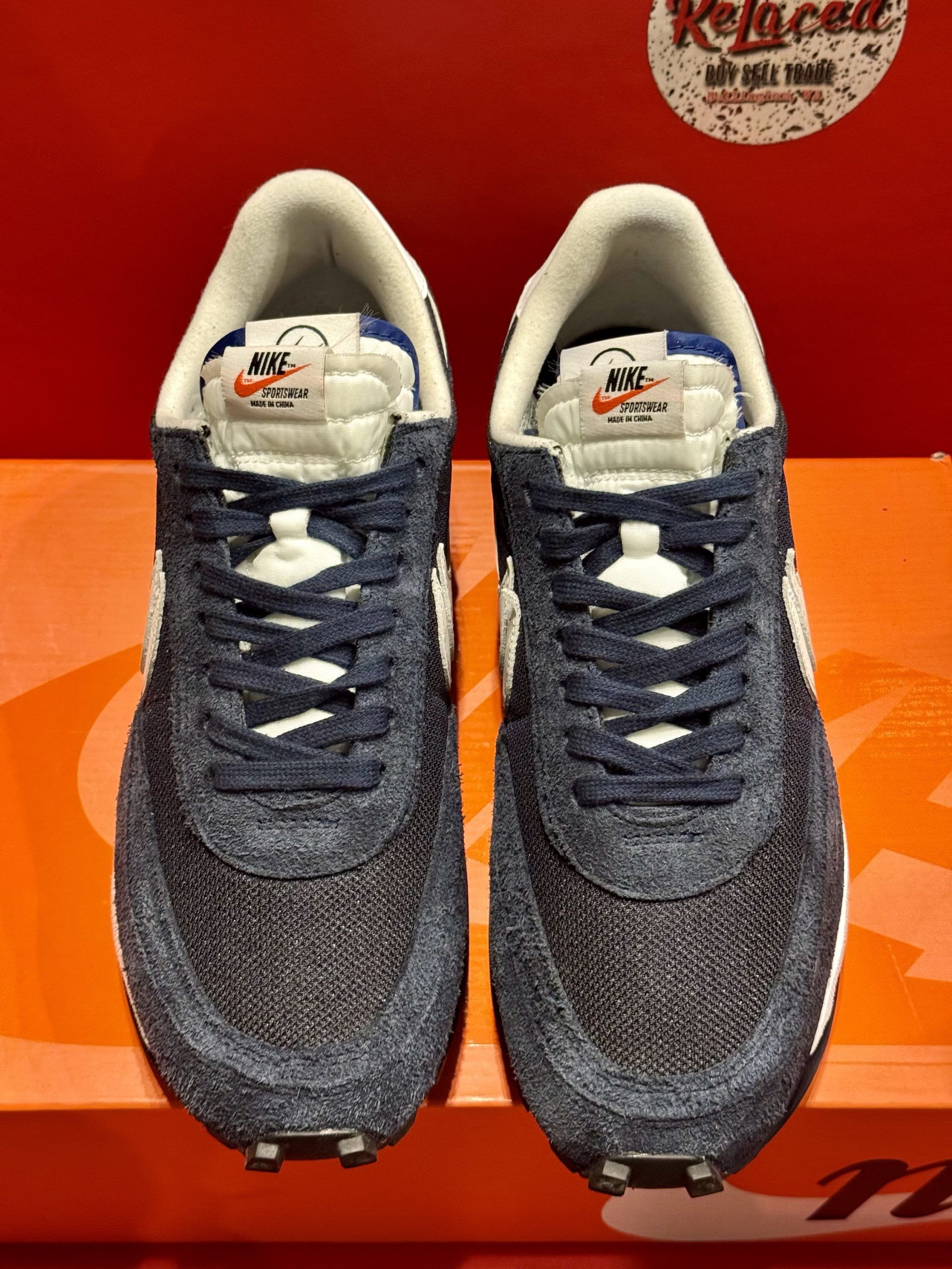 Nike sneakers, black and white, on an orange box, red backdrop.