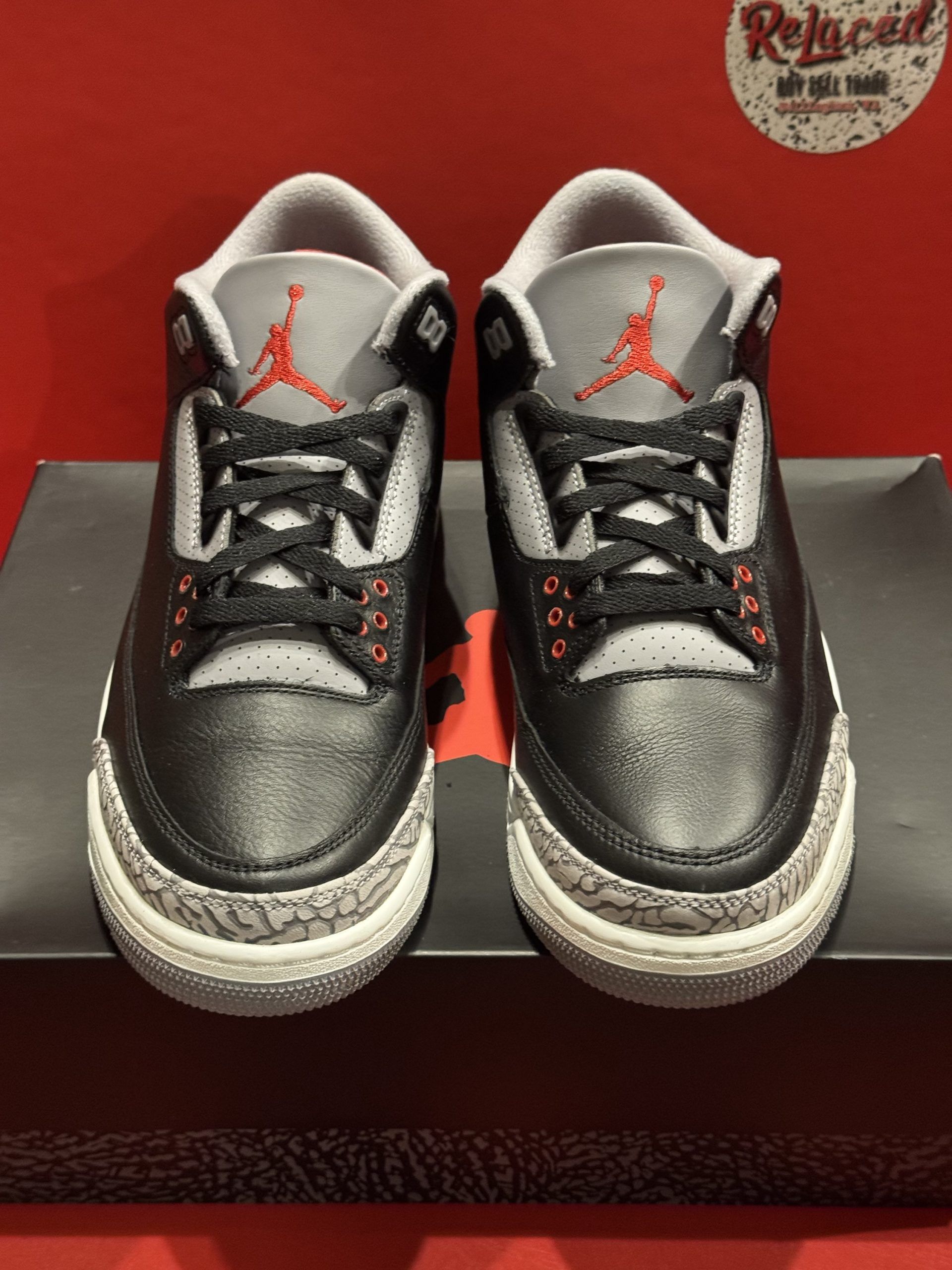 Air Jordan 3 black, grey, and red sneaker on box, sole visible.