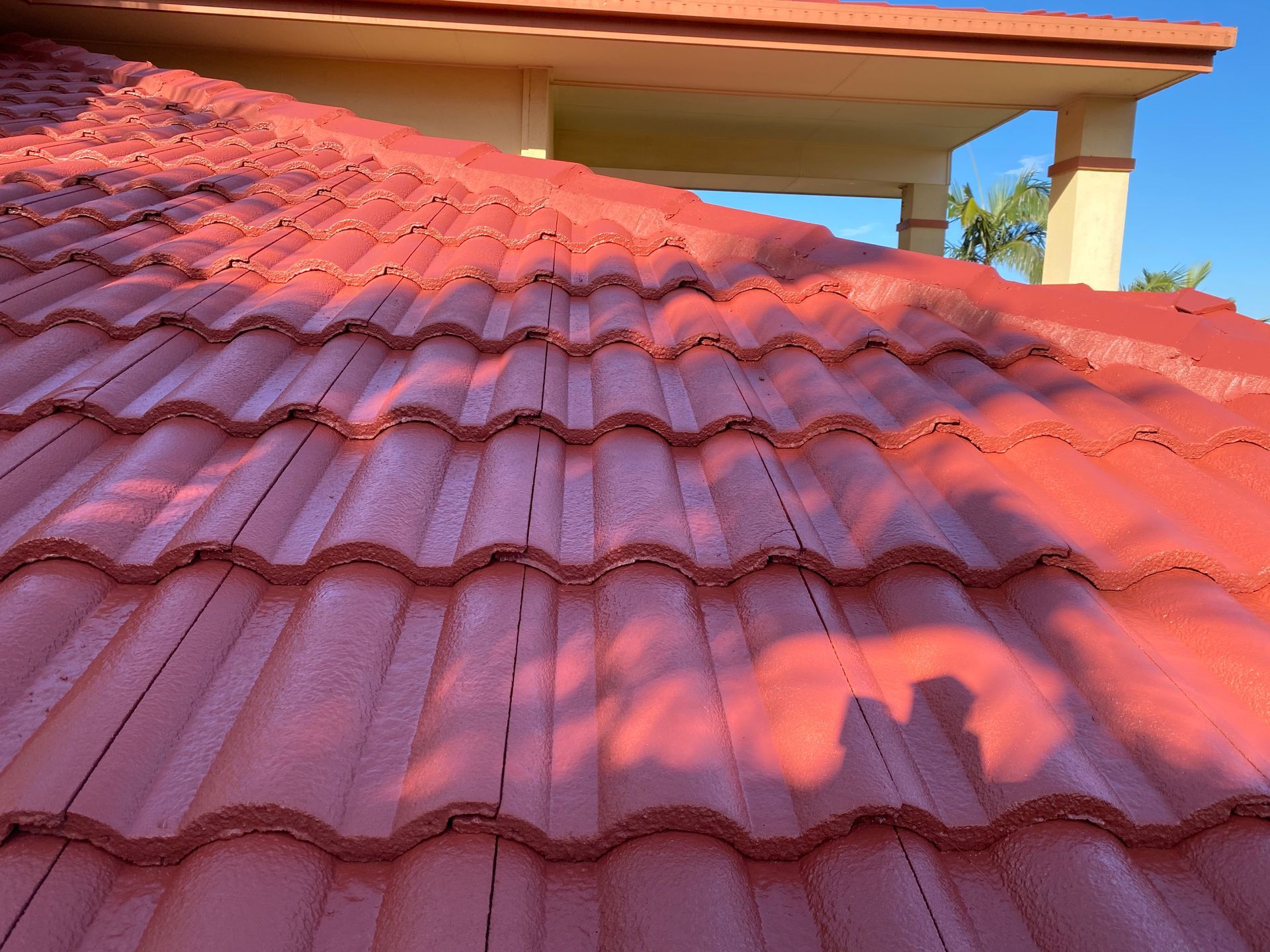 Red tile roof on a building with shadow of a person cast on it.
