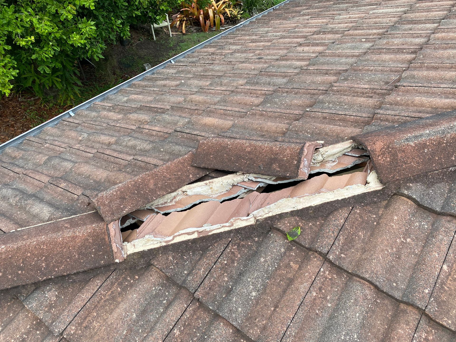 Damaged terracotta roof tiles; one tile is severely cracked and missing pieces.
