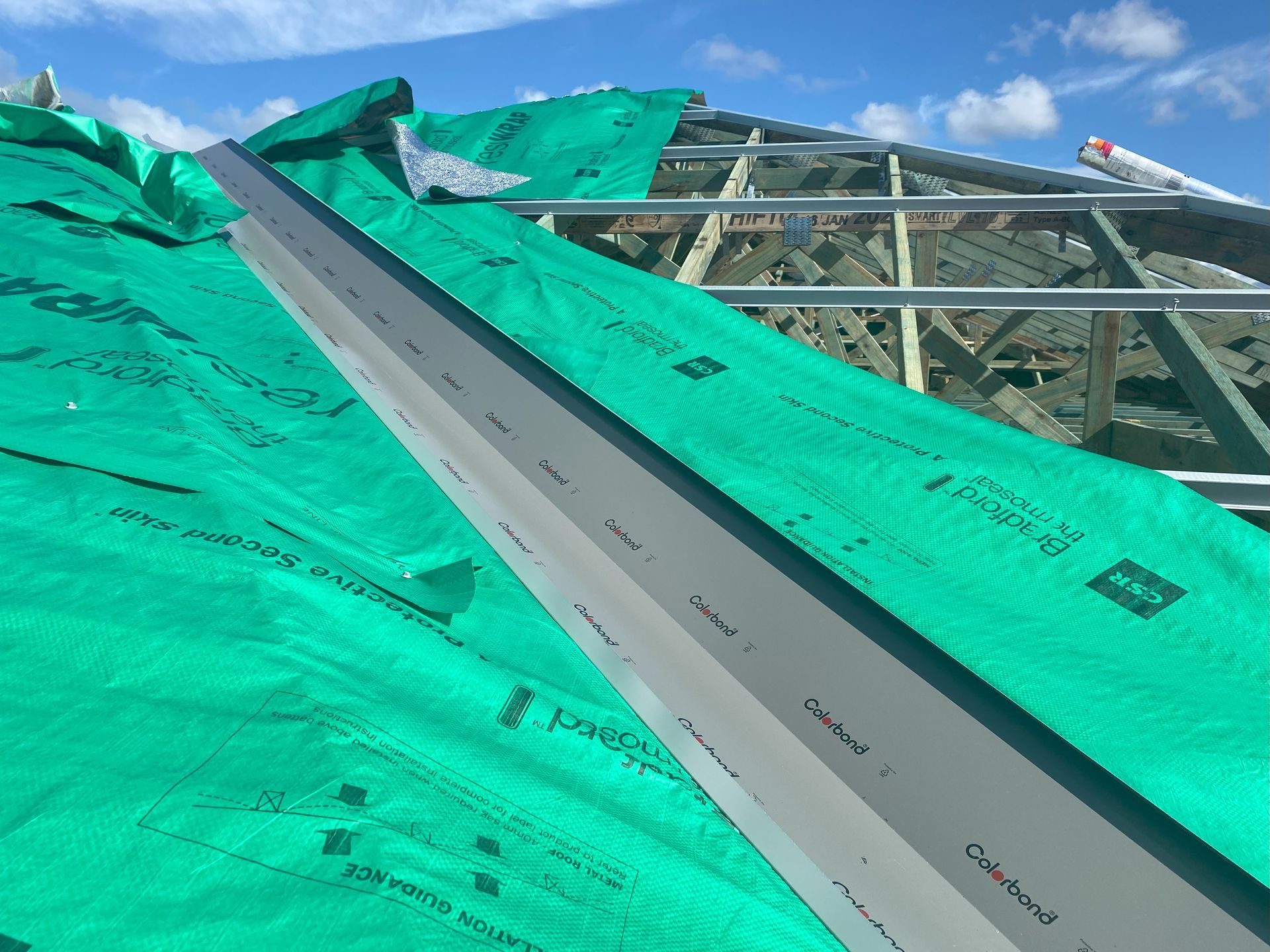 Green roofing underlayment with a metal flashing on a roof under construction.