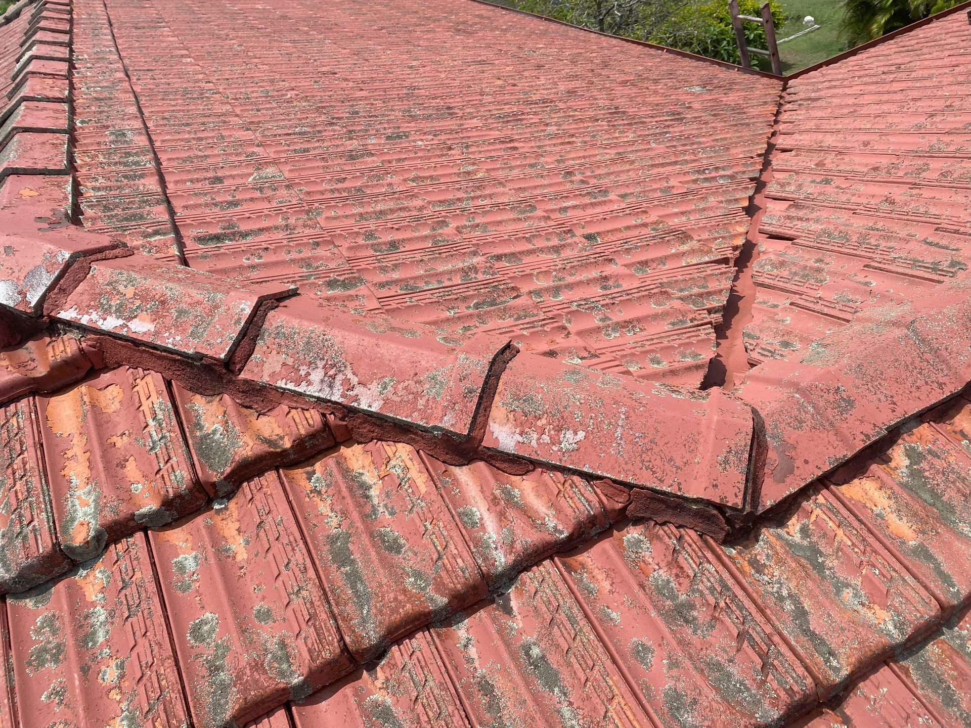 Red tile roof with peeling paint, weathered and showing signs of age and wear.