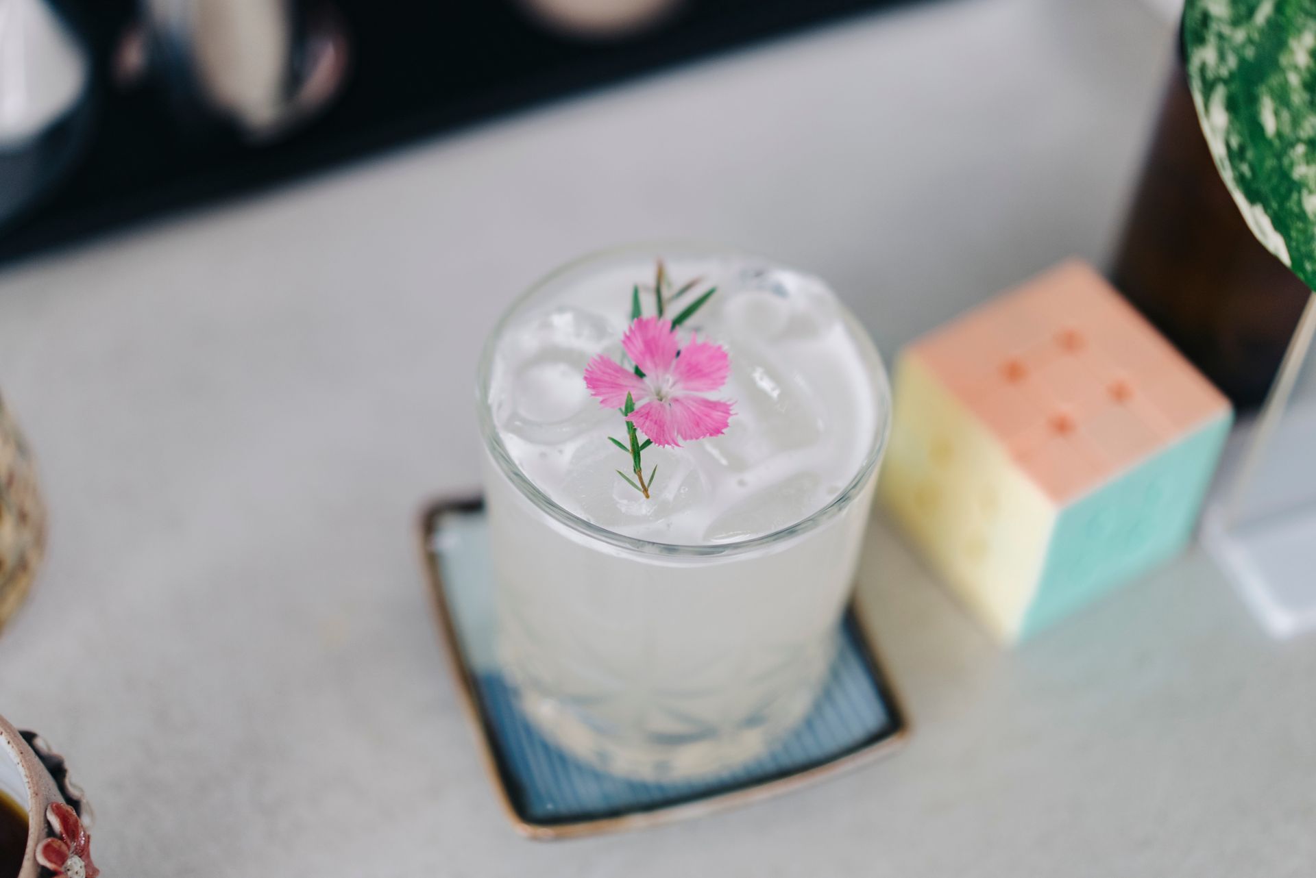 A close up of a drink with a flower on top of it on a table.