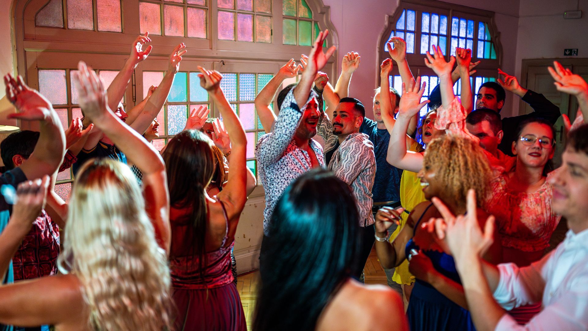 A crowd of people are dancing at a concert with their hands in the air.